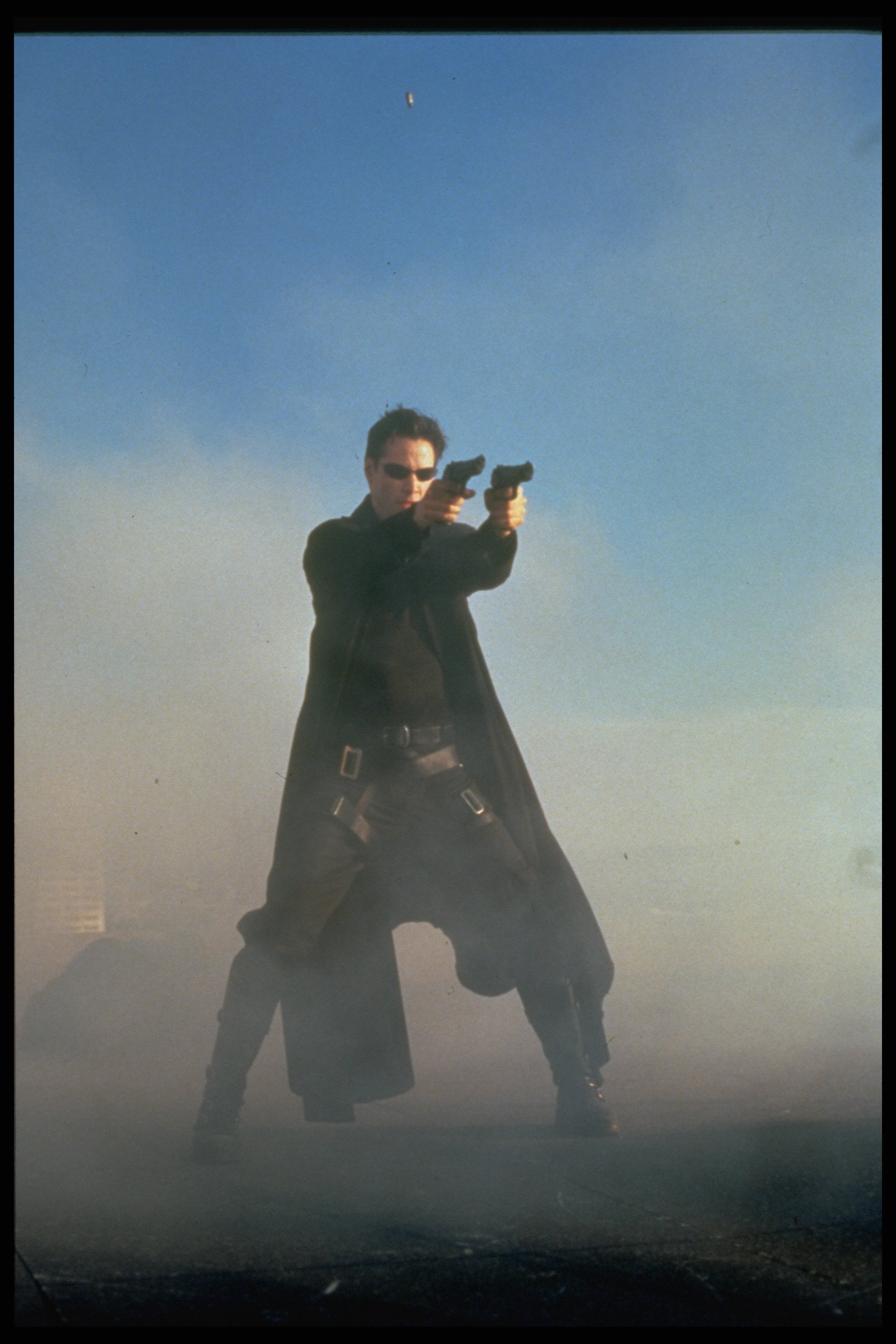 Keanu Reeves fires two guns on the rooftop in The Matrix