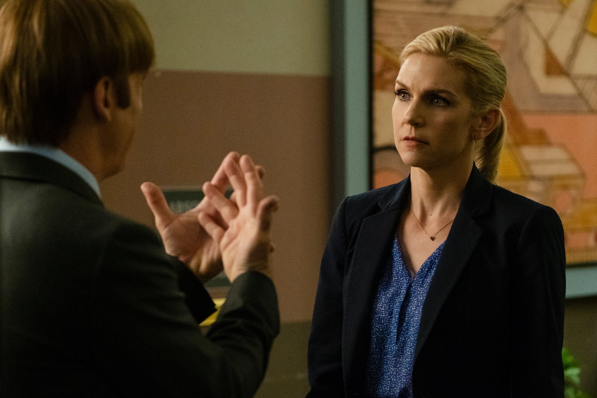 Rhea Seehorn as Kim Wexler in 'Better Call Saul' - She's wearing a blue shirt and black blazer and speaking to Jimmy, whose back is toward the camera
