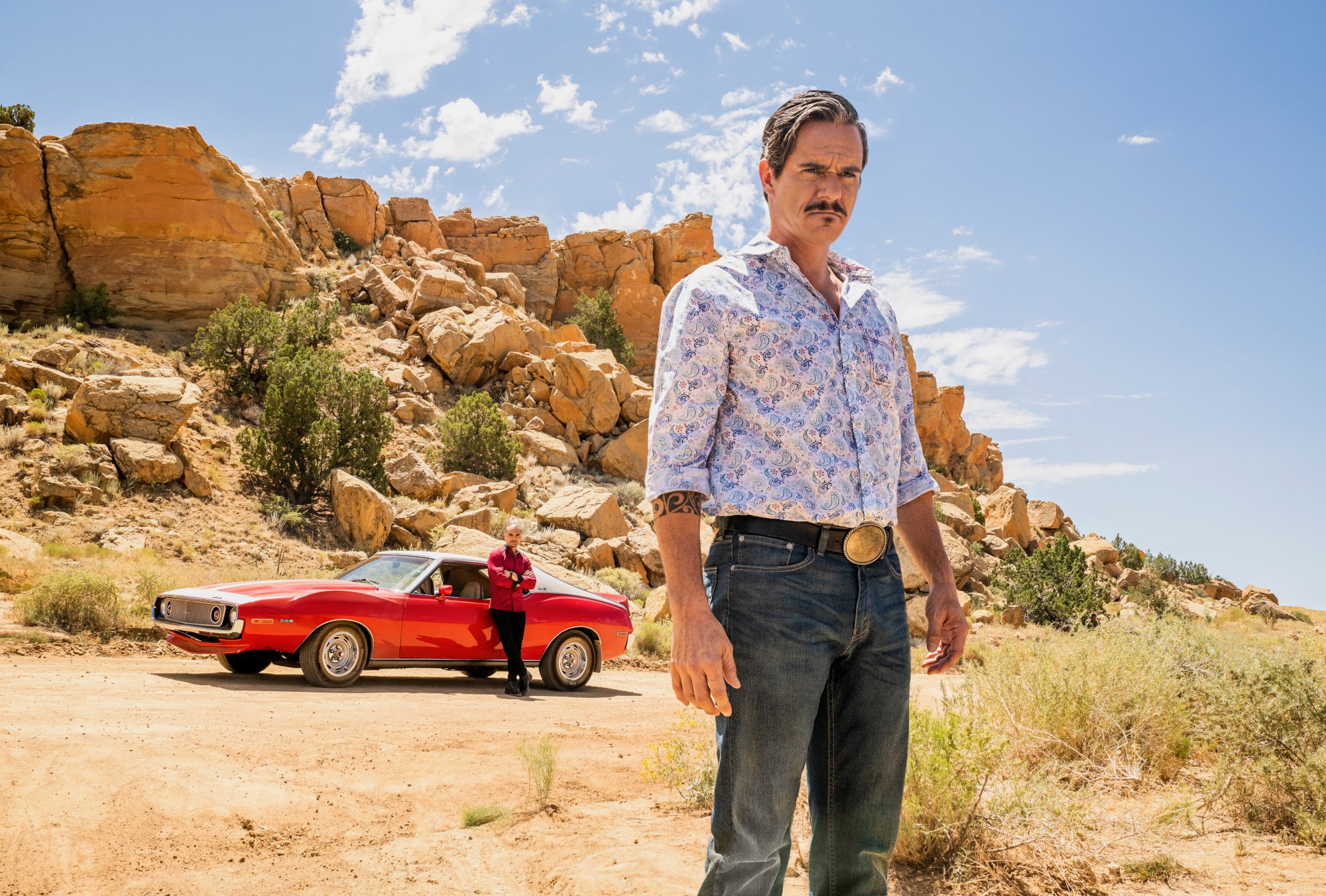 'Better Call Saul' star Tony Dalton as Lalo Salamanca - He's standing in a desert with a red car behind him. Michael Mando is leaning against the car, playing Nacho Varga.