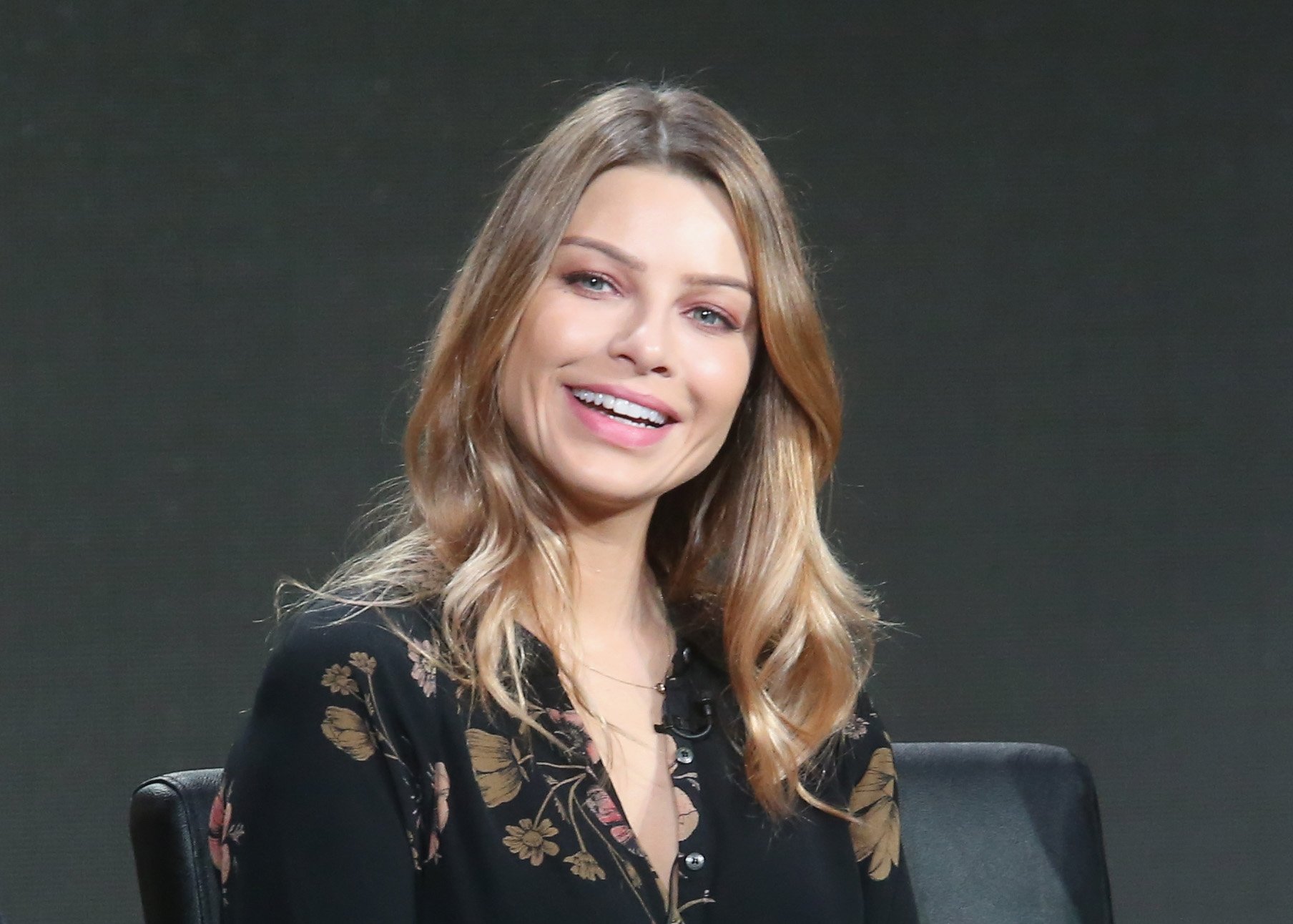 Lauren German laughing in front of a gray background