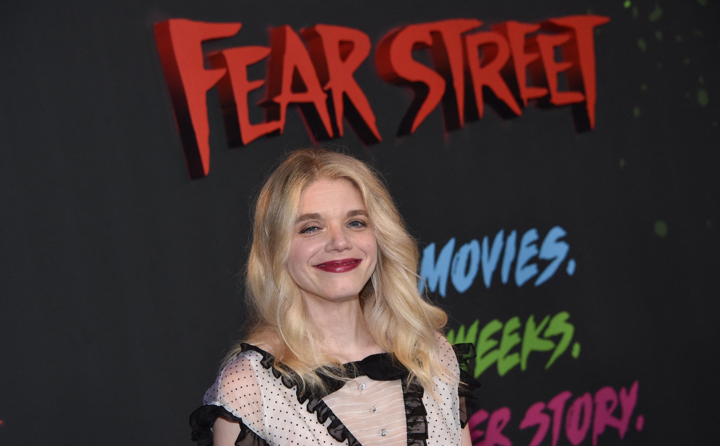 Fear Street Part 2 director Leigh Janiak wearing an off-white and black dress in front of a Netflix wall