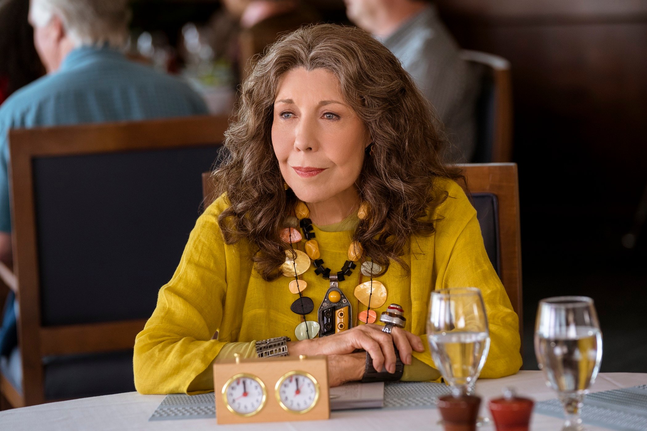 Lily Tomlin sits at a table during the filming of 'Grace and Frankie'