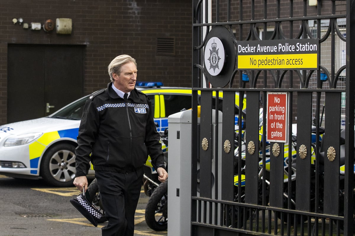 Adrian Dunbar standing outside a police station while filming 'Line of Duty'