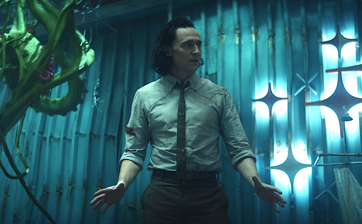 Tom Hiddleston in a shirt and tie in 'Loki' Episode 5 on Disney+. He stands looking concerned in an underground bunker built by other Lokis.