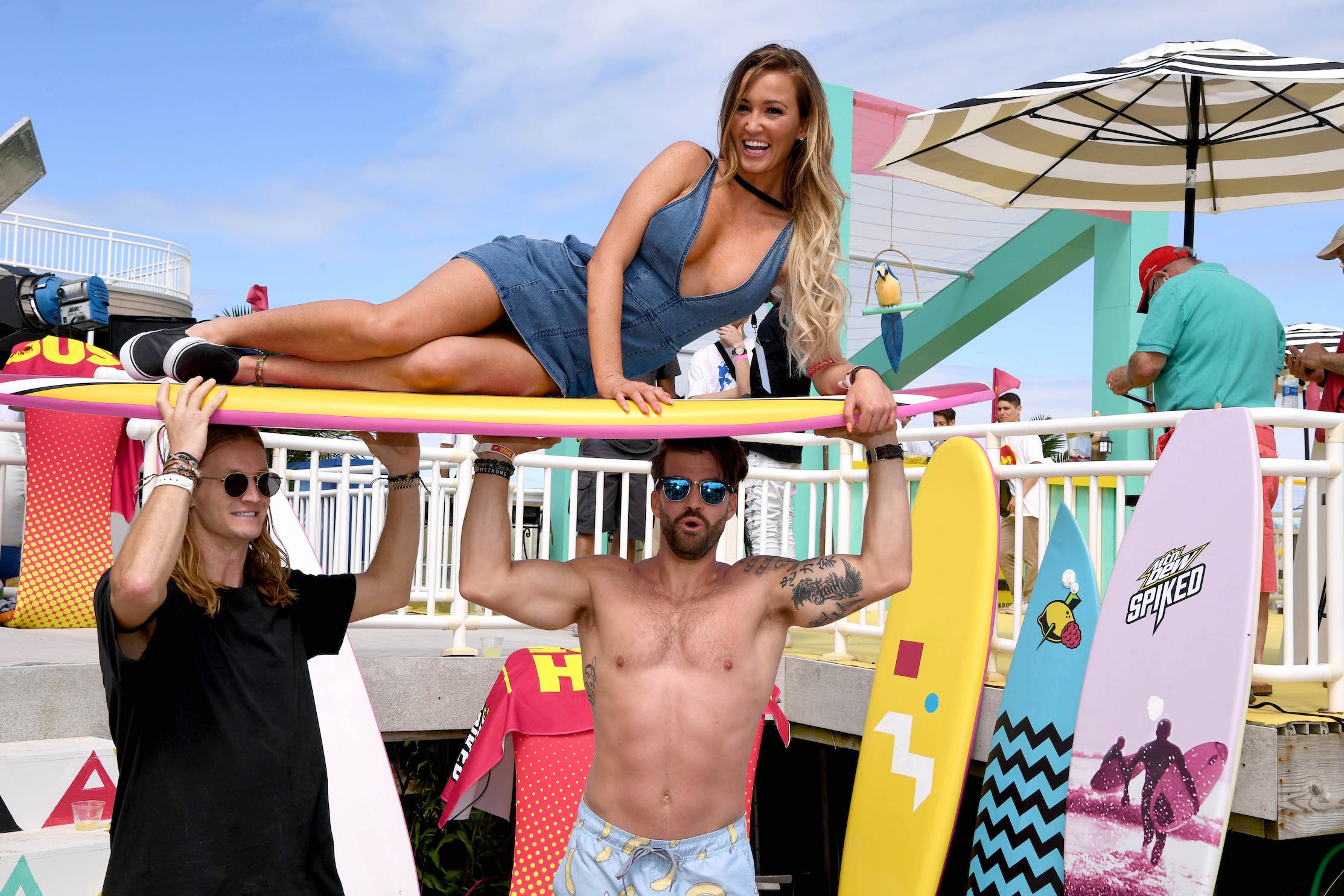 Ashley Mitchell from MTV's 'The Challenge' on top of a surfboard held up by Johnny 'Bananas' Devenanzio and Rory Kramer while they're all at the beach