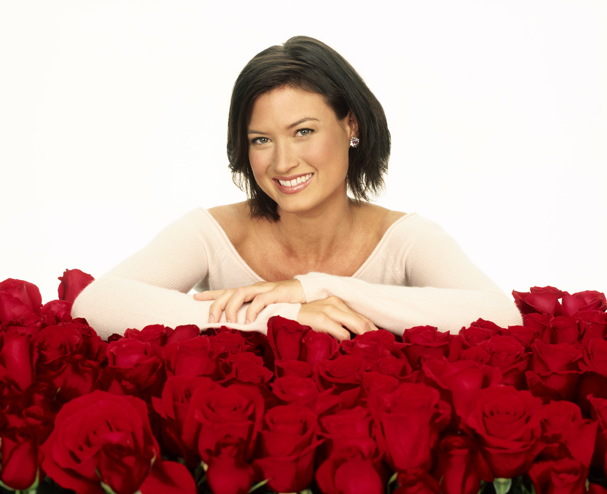 Meredith Phillips smiling, leaning over roses