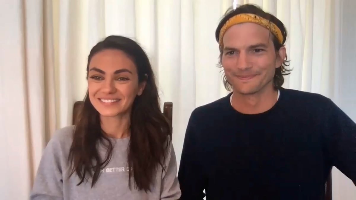 Mila Kunis and Ashton Kutcher smiling on camera for an interview