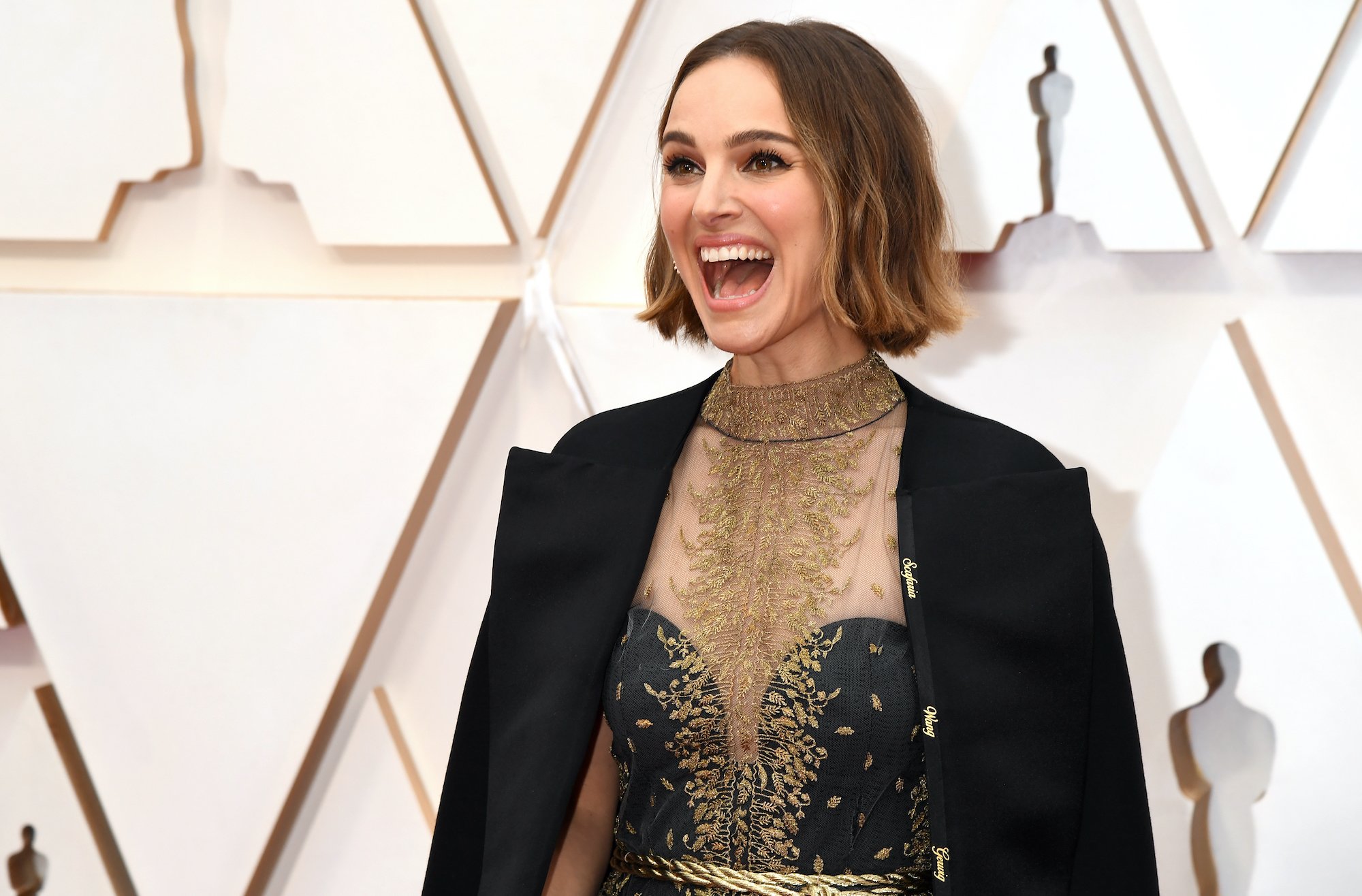 Natalie Portman laughing in front of a white background
