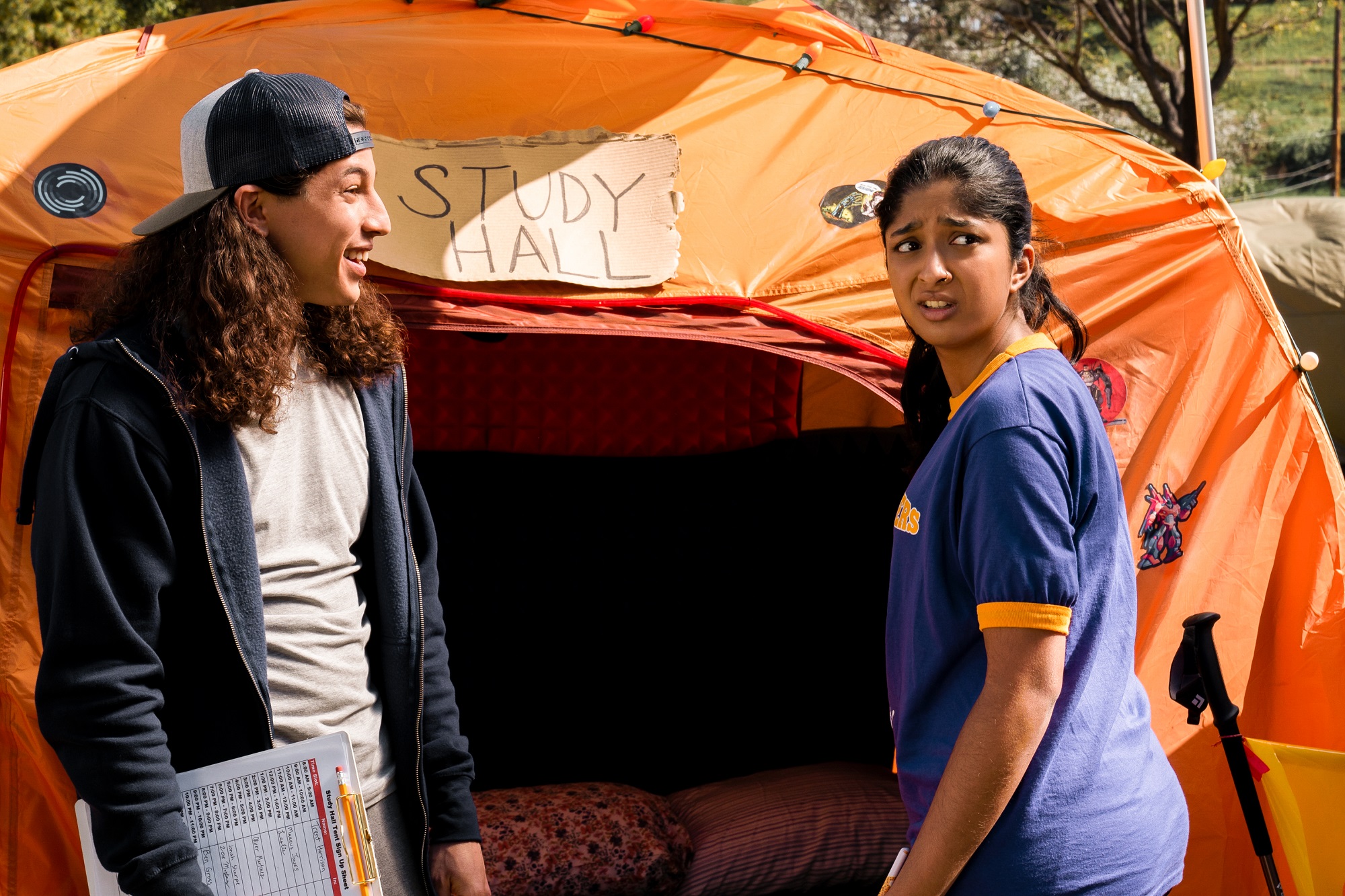 Trent and Devi stand in front of an orange tent in 'Never Have I Ever'