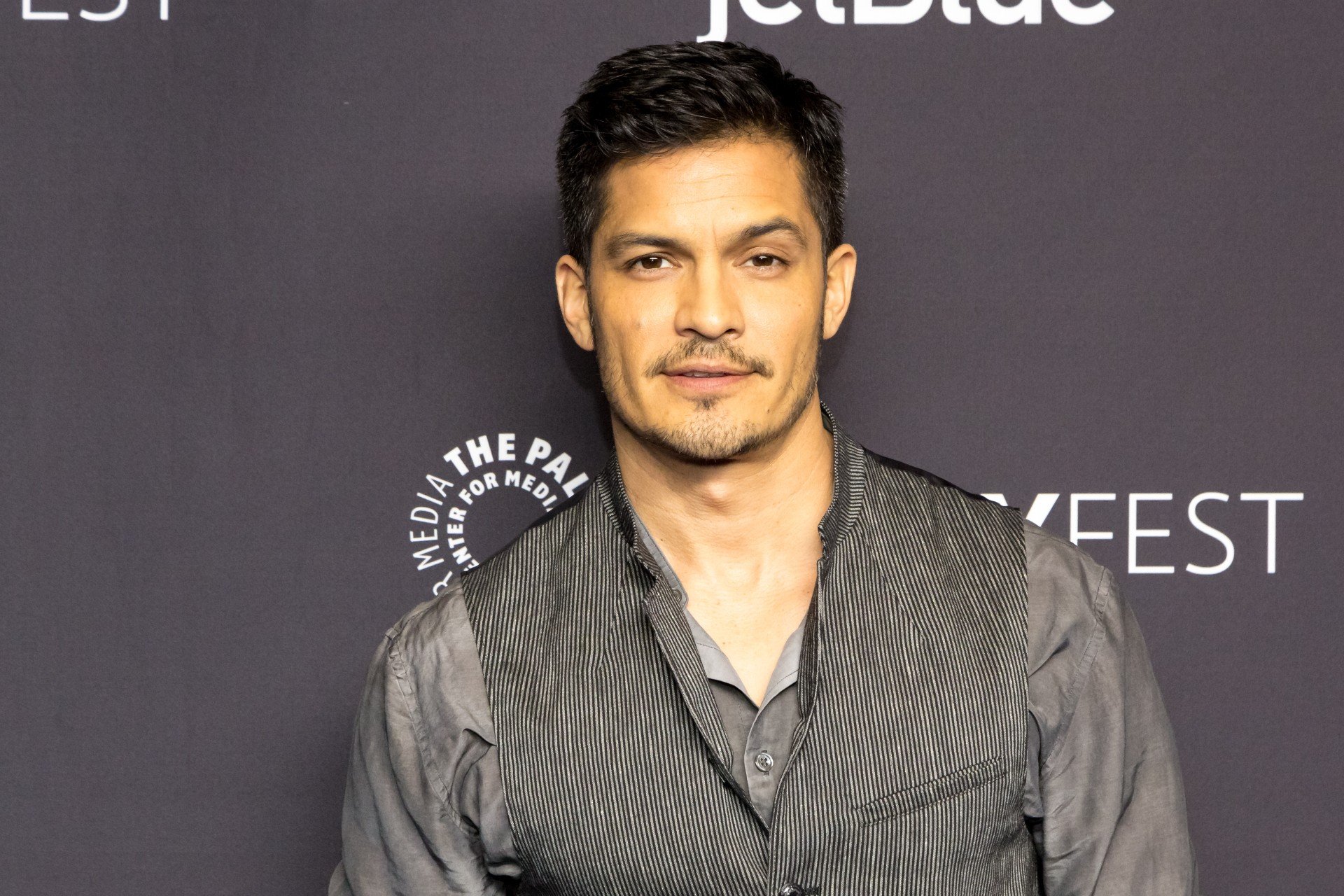 Nicholas Gonzalez wears a dark vest and dress shirt at a media event.