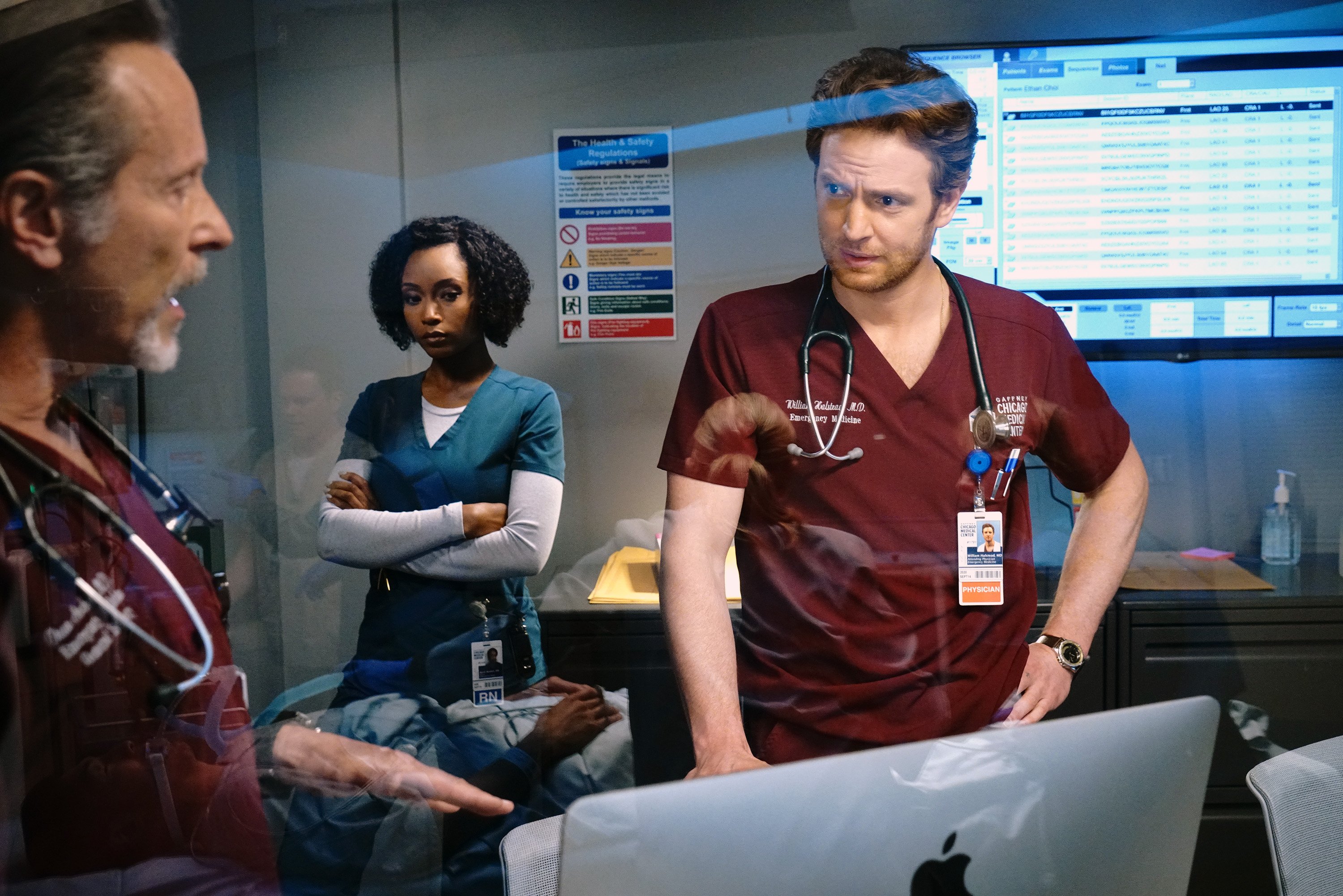 Dean Archer, Will Halstead and April Sexton talk in front of an Apple Computer during a scene on 'Chicago Med'