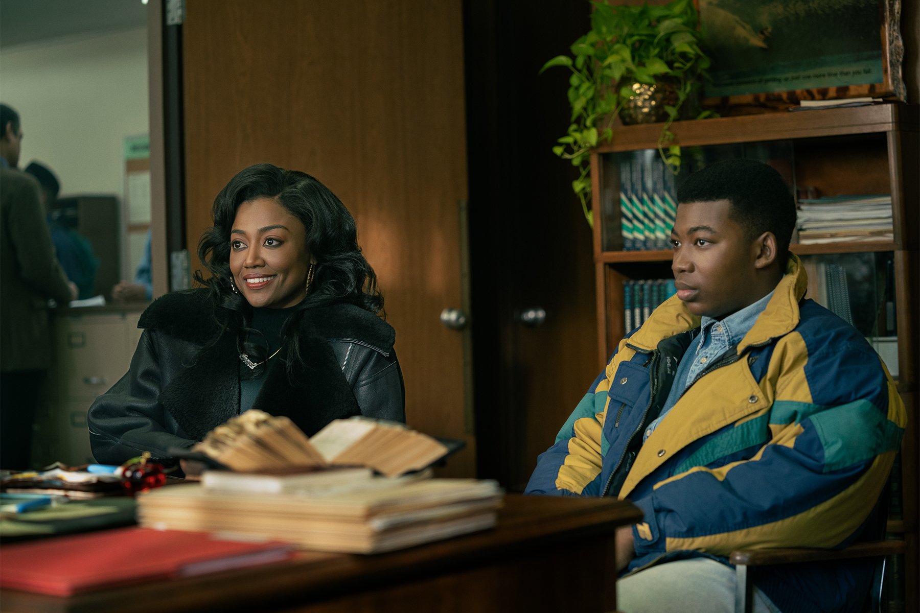 In a scene from ‘Power Book III: Raising Kanan,’ actors Patina Miller and Mekai Curtis sit side-by-side in front of a desk as their characters Raquel “Raq” Thomas and Kanan Stark.