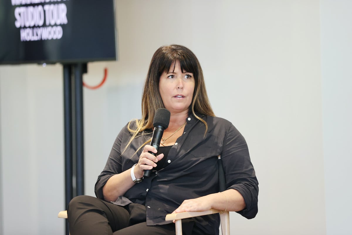 Patty Jenkins wears black and holds a microphone