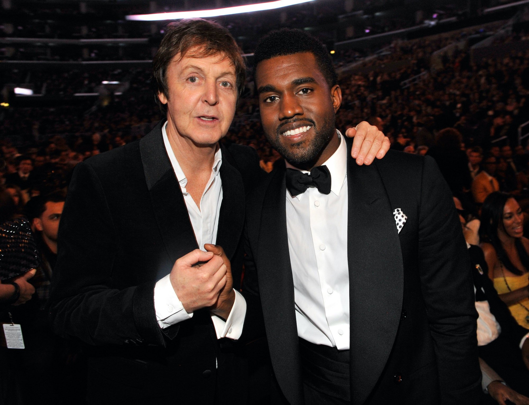 Paul McCartney and Kanye West smiling in front of a large crowd