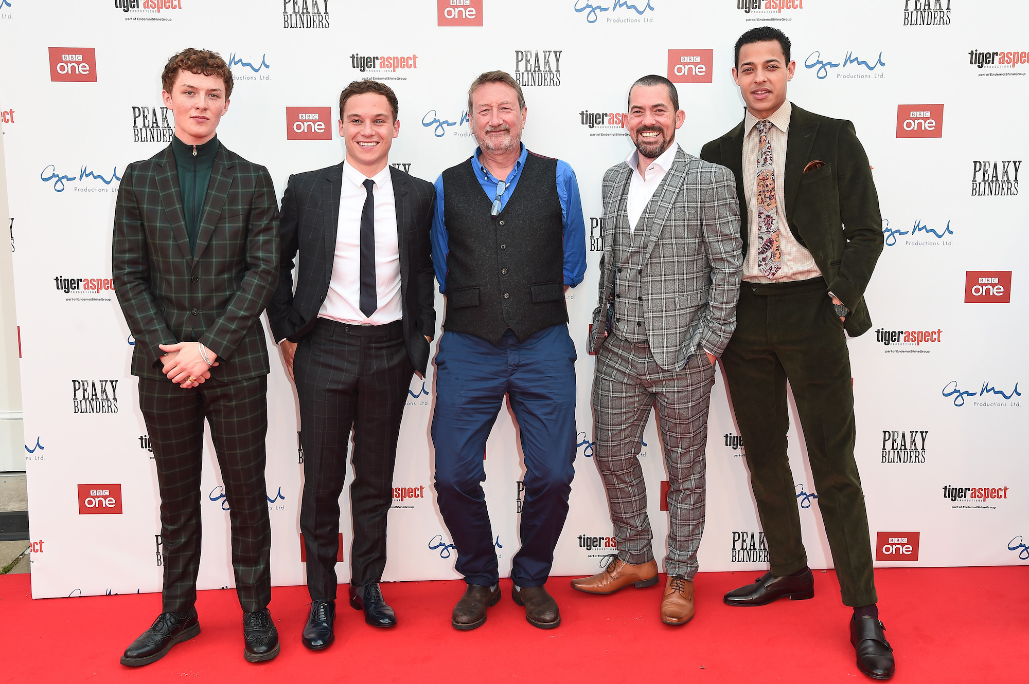 Steven Knight, creator of 'Peaky Blinders' Season 6, in the middle of actors Harry Kirton, Finn Cole, Packy Lee, and Daryl McCormack standing for a photo on a red carpet
