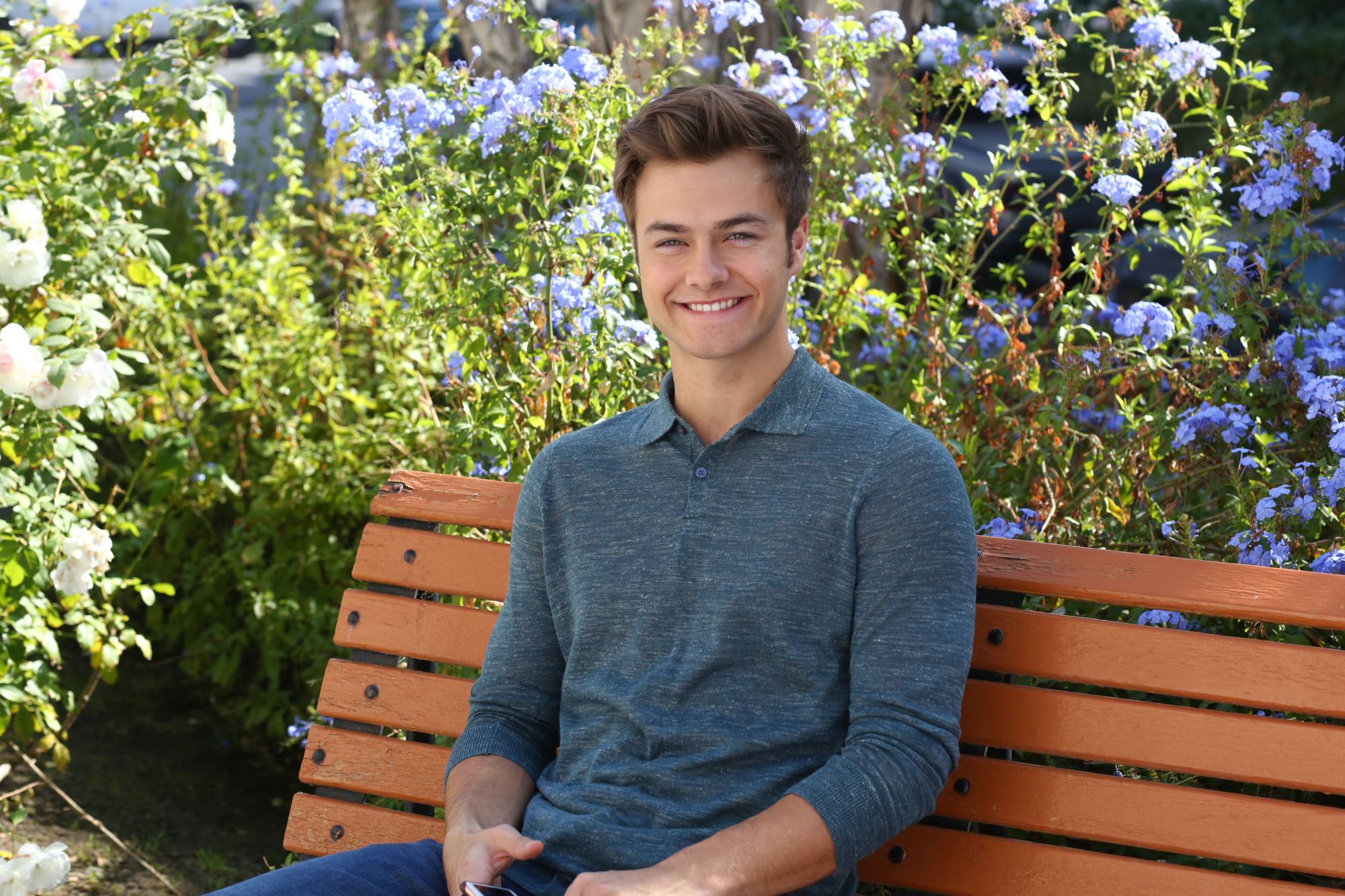 Peyton Meyer sitting on a bench for an 'American Housewife' press photo