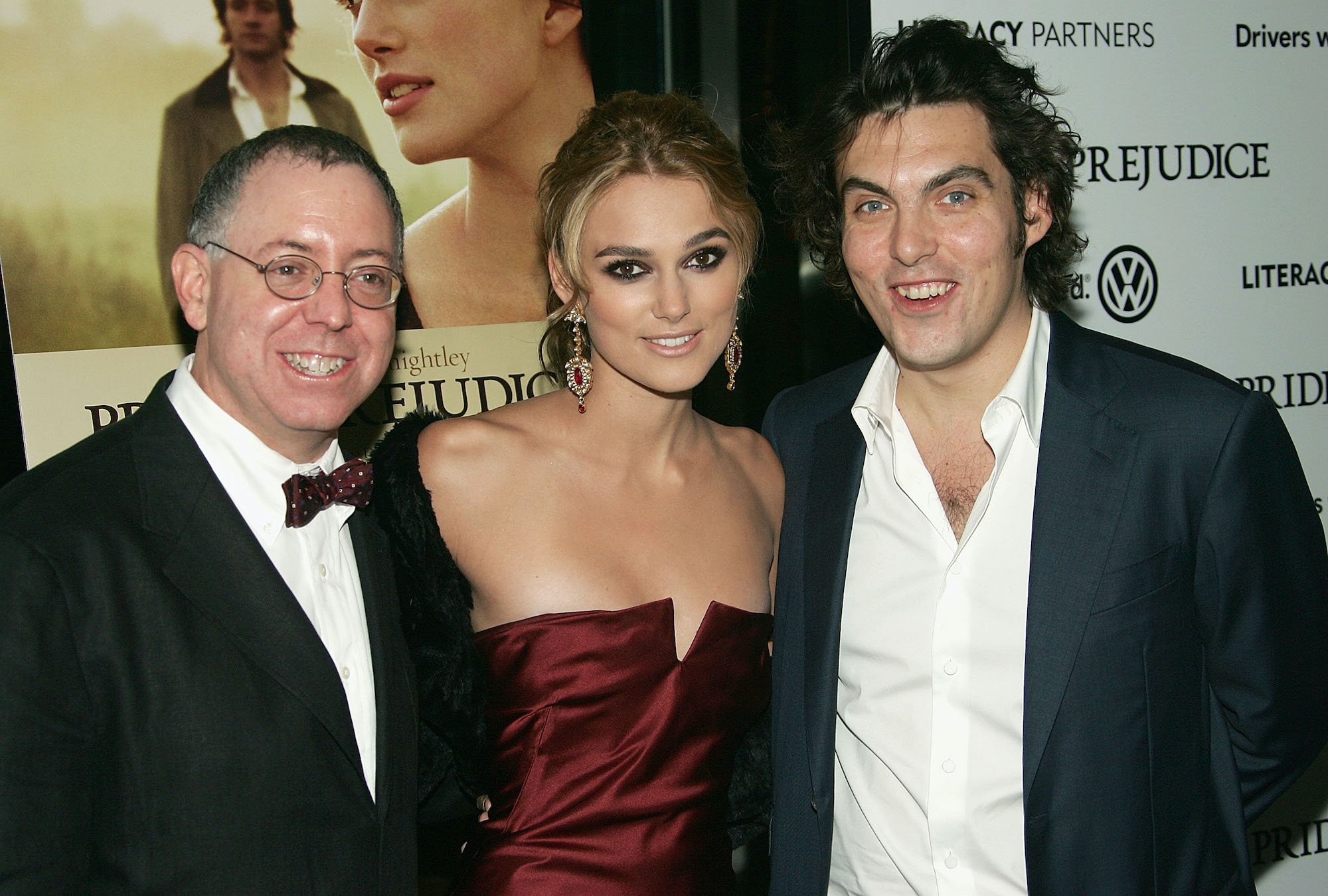 James Schamus, Keira Knightley and Joe Wright smiling in front of a 'Pride and Prejudice' poster