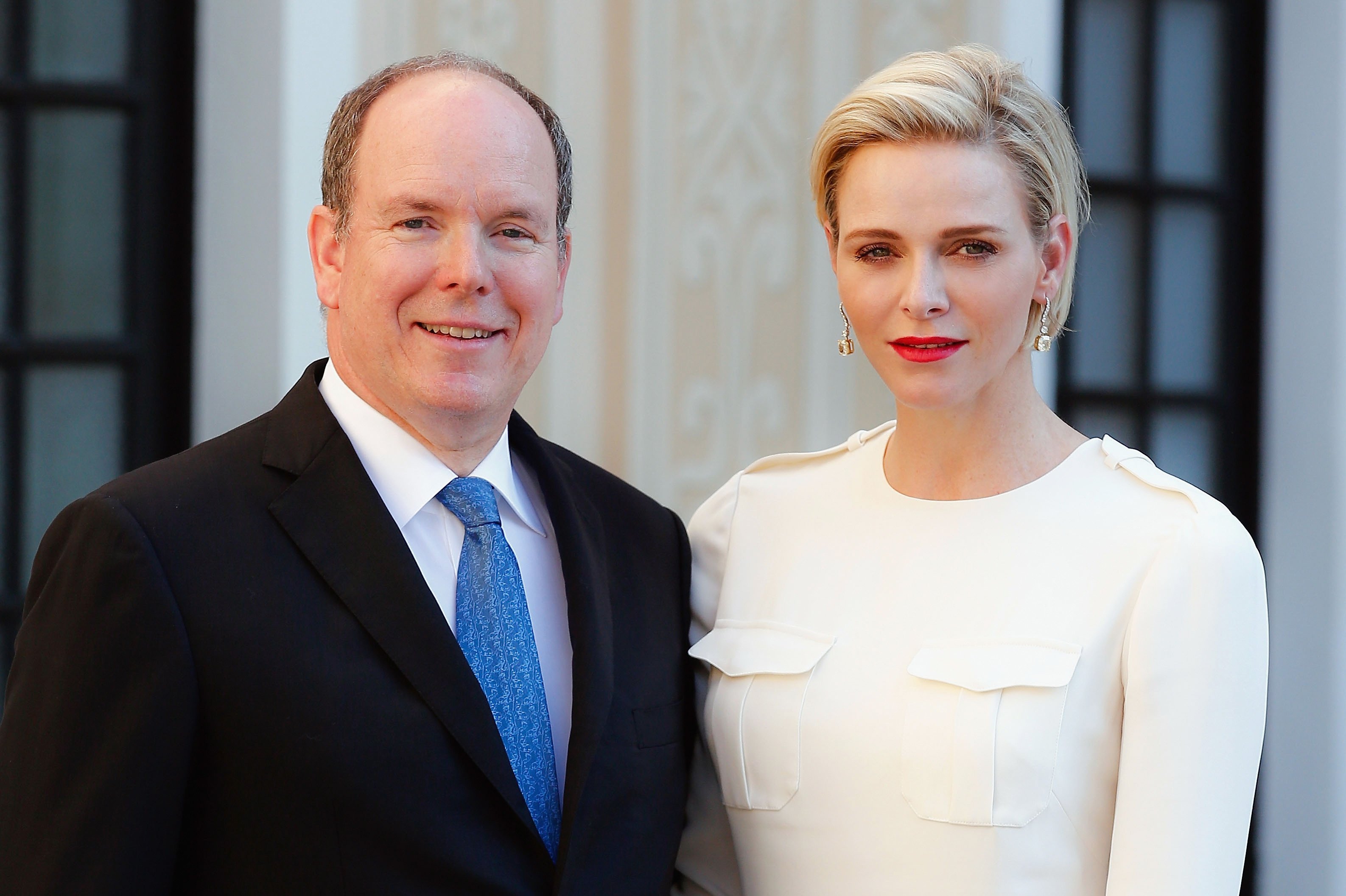 Prince Albert II of Monaco dressed in a suit and Princess Charlene of Monaco in a white outfit at Monaco Palace cocktail party
