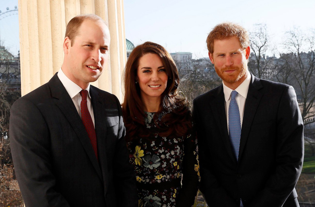 Prince William, Kate Middleton, and Prince Harry standing next to each other, smiling