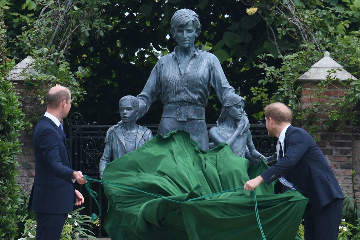 Prince William and Prince Harry pull a green cloth away to reveal a statue of their late mother, Princess Diana