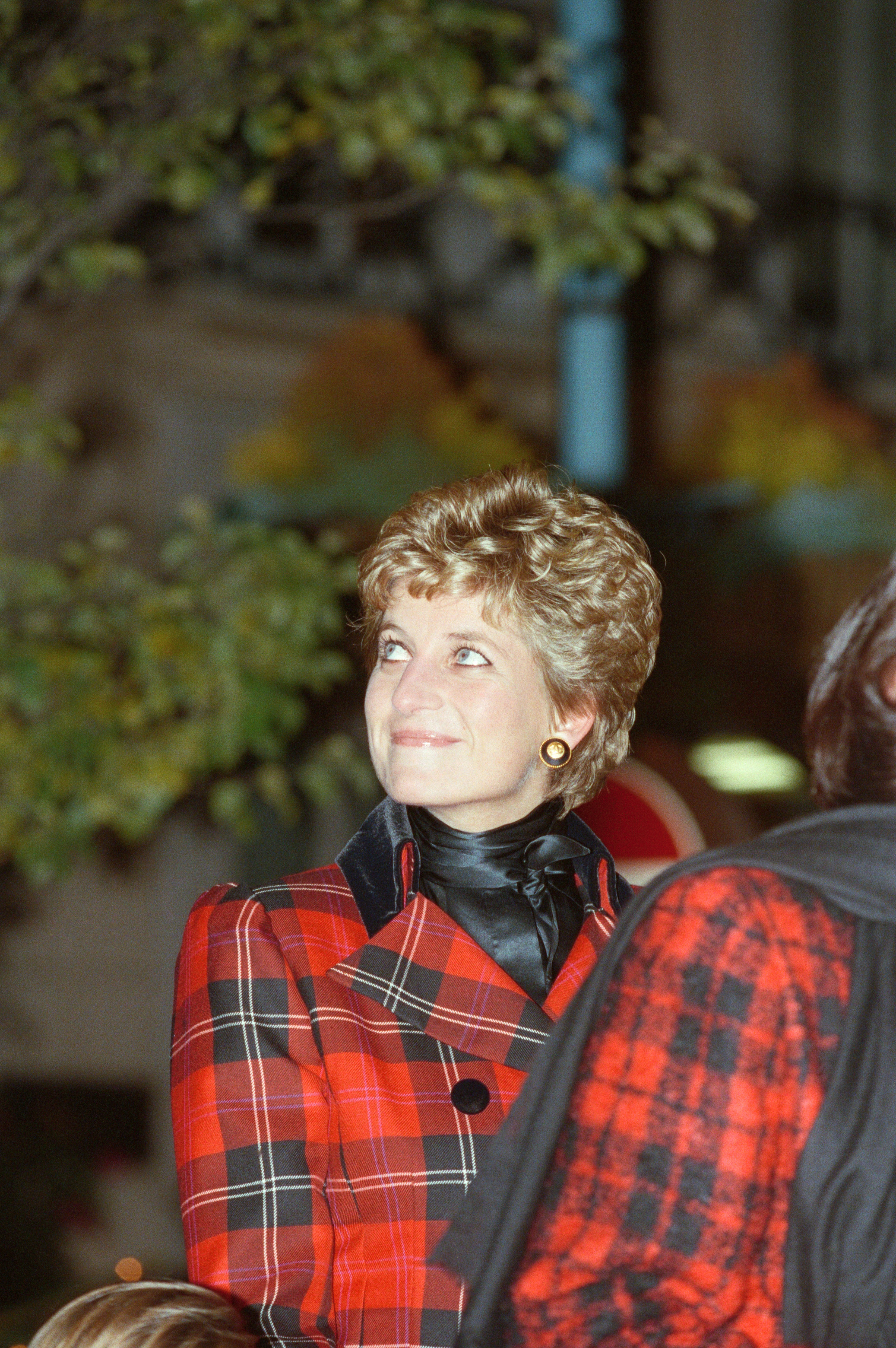 Princess Diana in a Christmas photo, looking up and smiling while she switches on Christmas lights