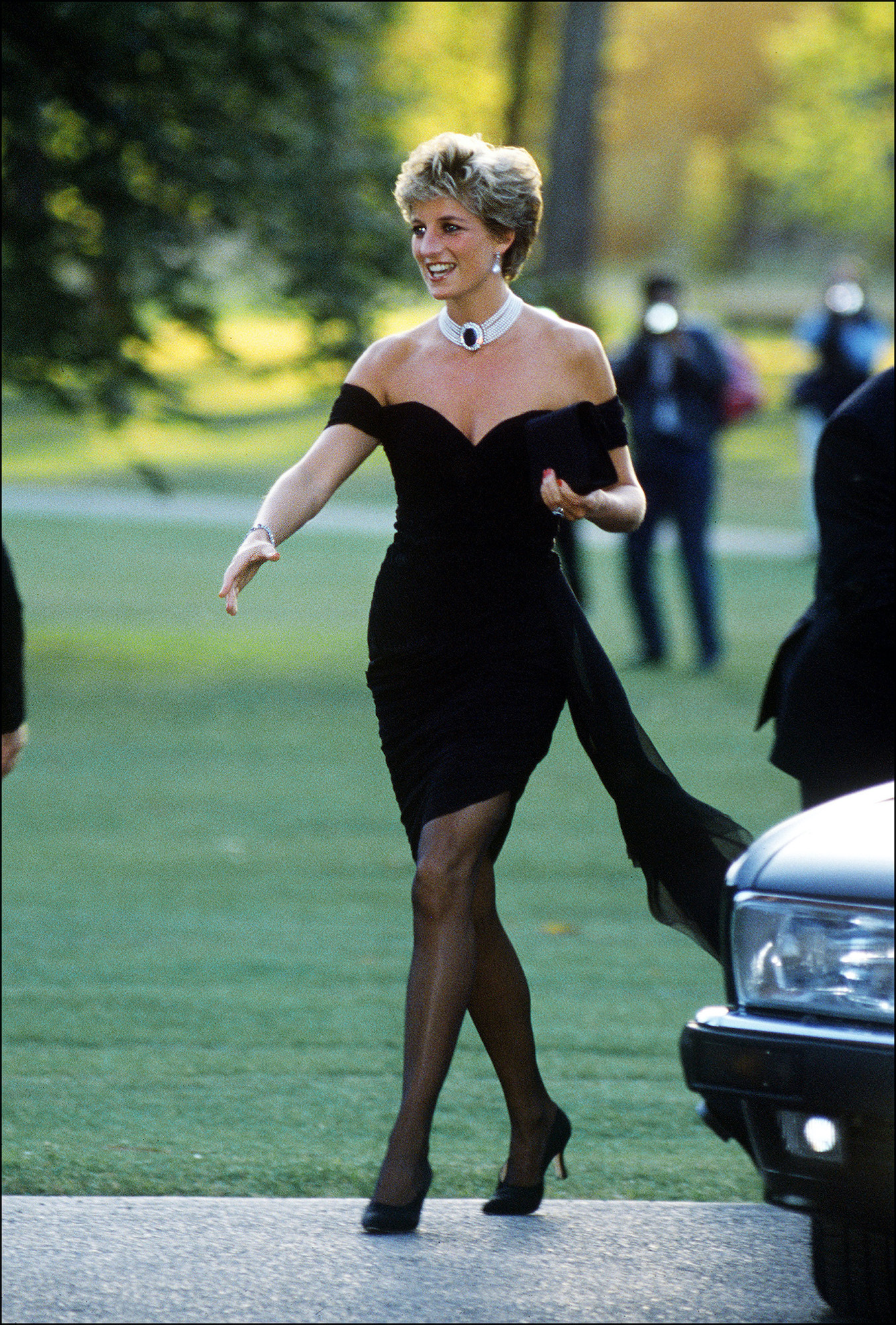 Princess Diana smiling, in an off-shoulder dark color dress