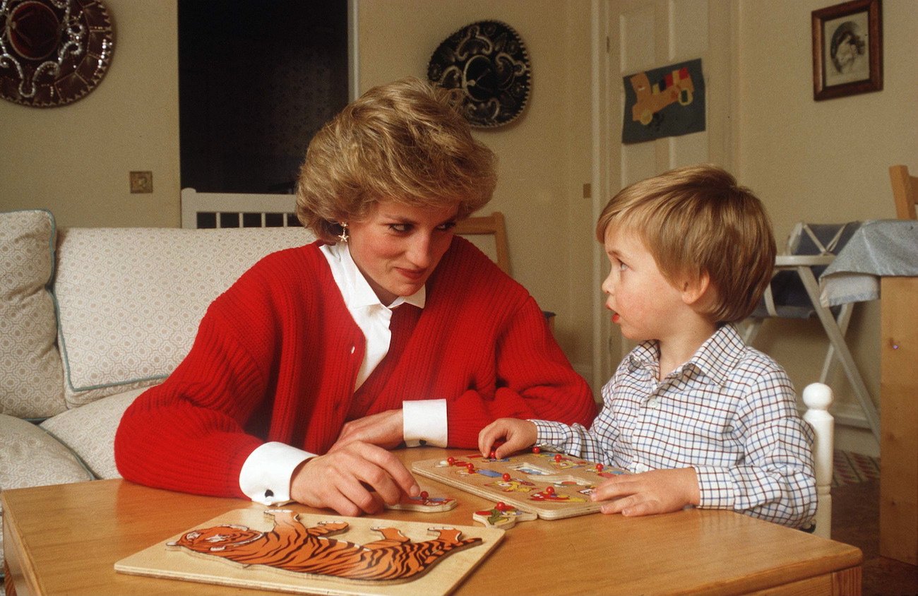 Princess Diana and young Prince William seated at a table with a puzzle, looking at each other