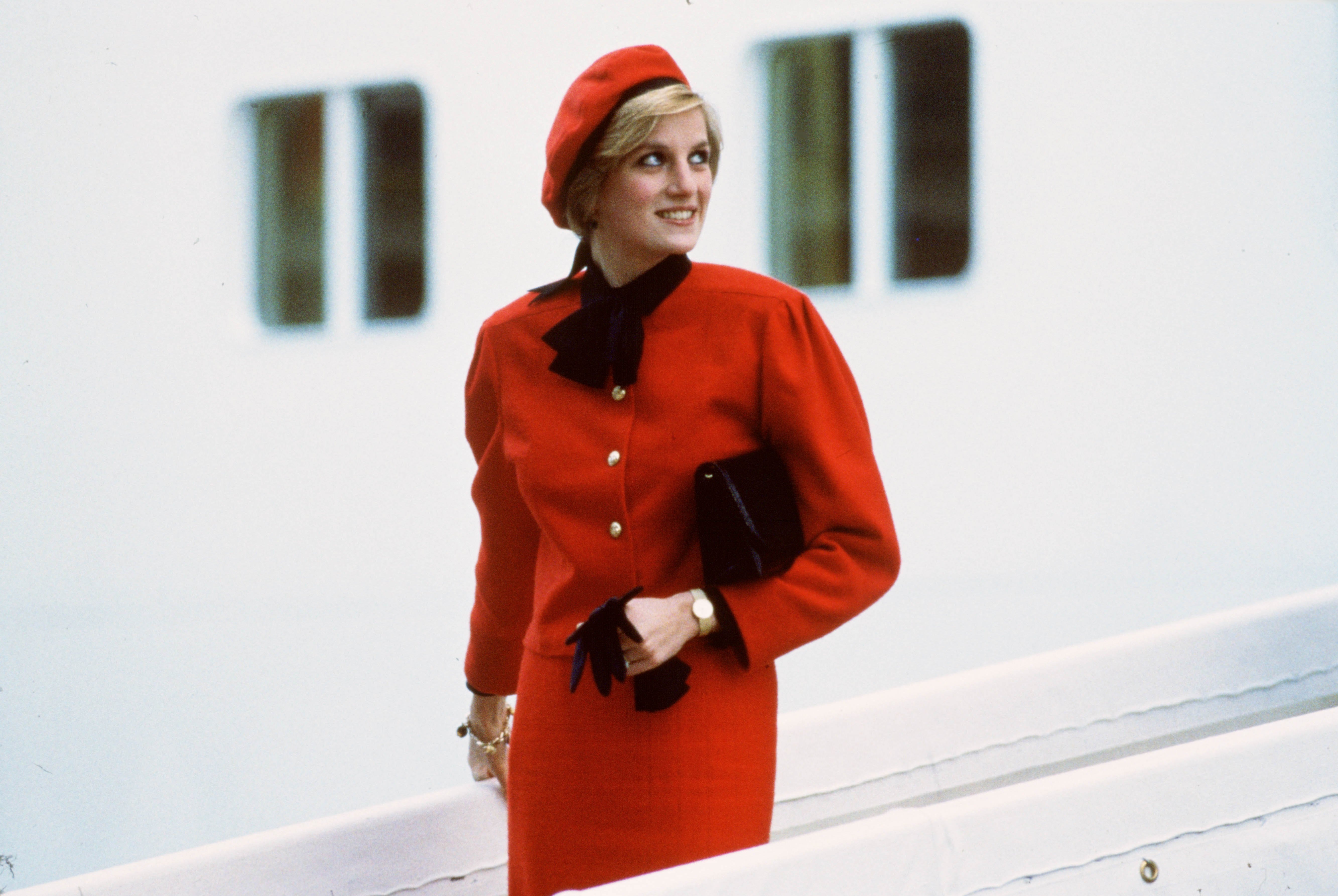 Princess Diana dressed in all red and carrying a black purse aboard the P&O cruise liner Royal Princess