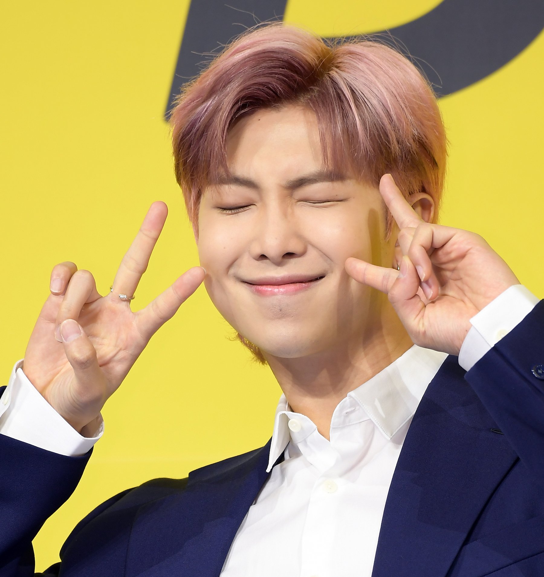 RM of BTS attends a press conference for BTS's new digital single 'Butter', with pink hair throwing up peace signs