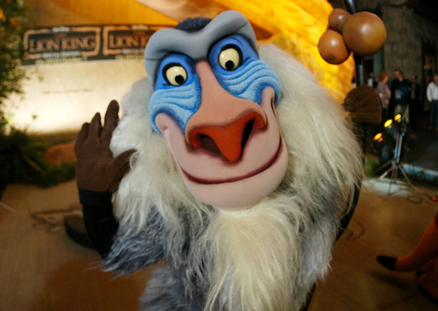 A close up of Rafiki the monkey from 'The Lion King' with a slightly blurred background that has an orangish tint.