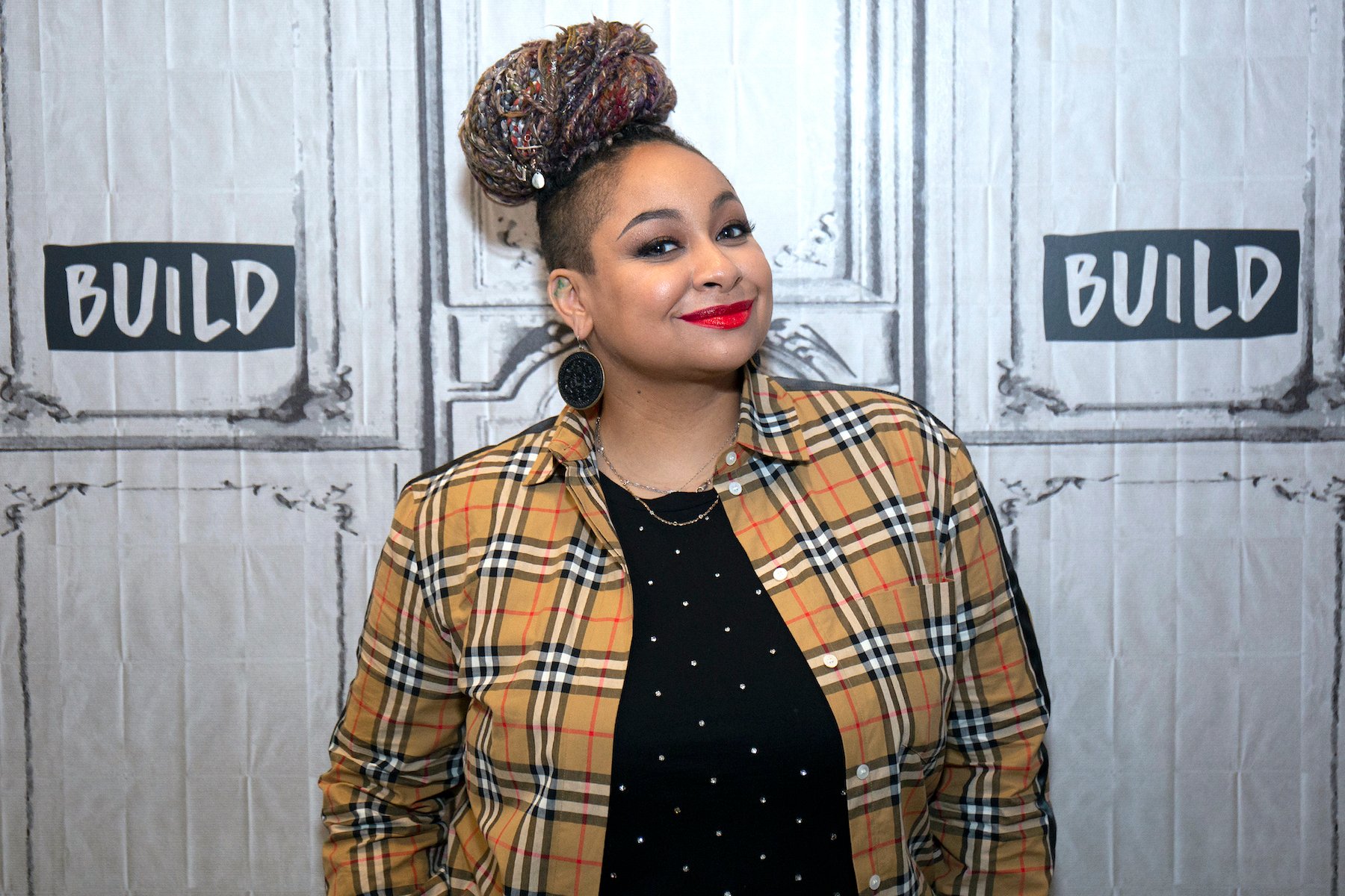 Raven Symone smiling in front of a white background