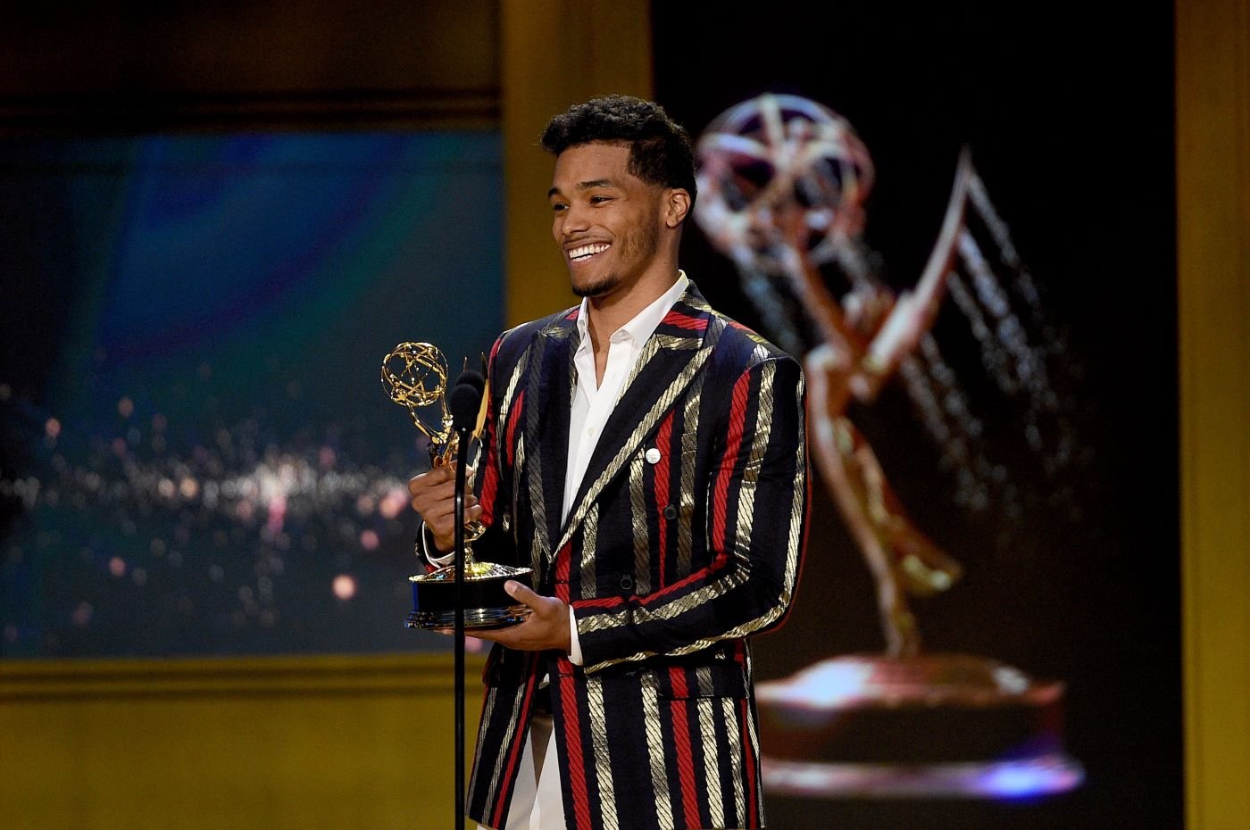 Robin Flynn from 'The Bold and the Beautiful' that played Zende accepting an award in a black, gold, and red striped suit jacket and white button-up shirt.