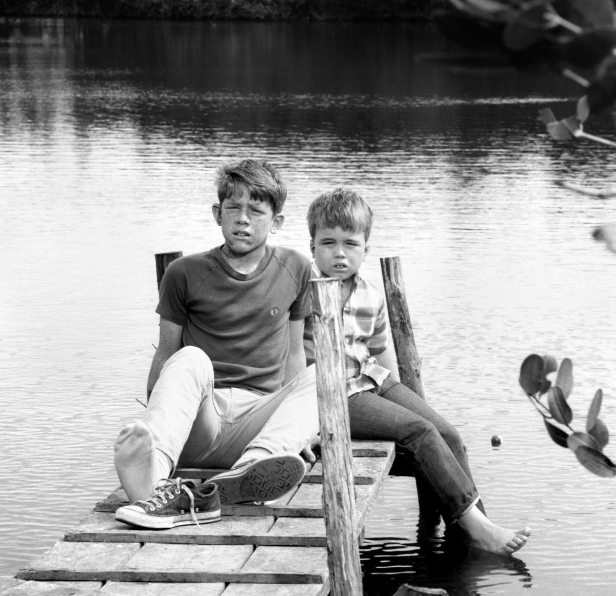 Ron and Clint Howard sit on a dock on the set of 'Gentle Ben'