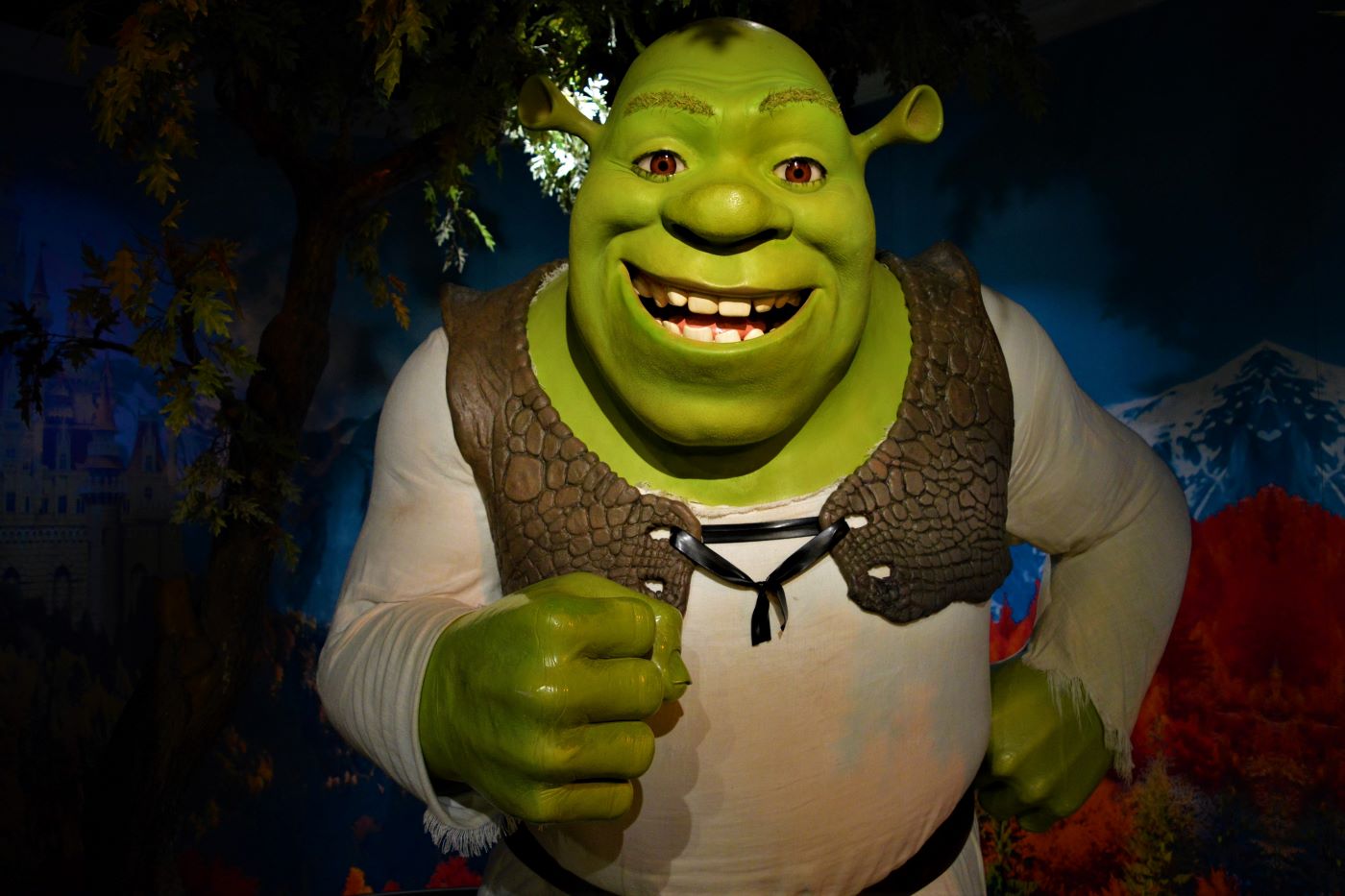 Shrek, the character, stands in front of a wooded scene.