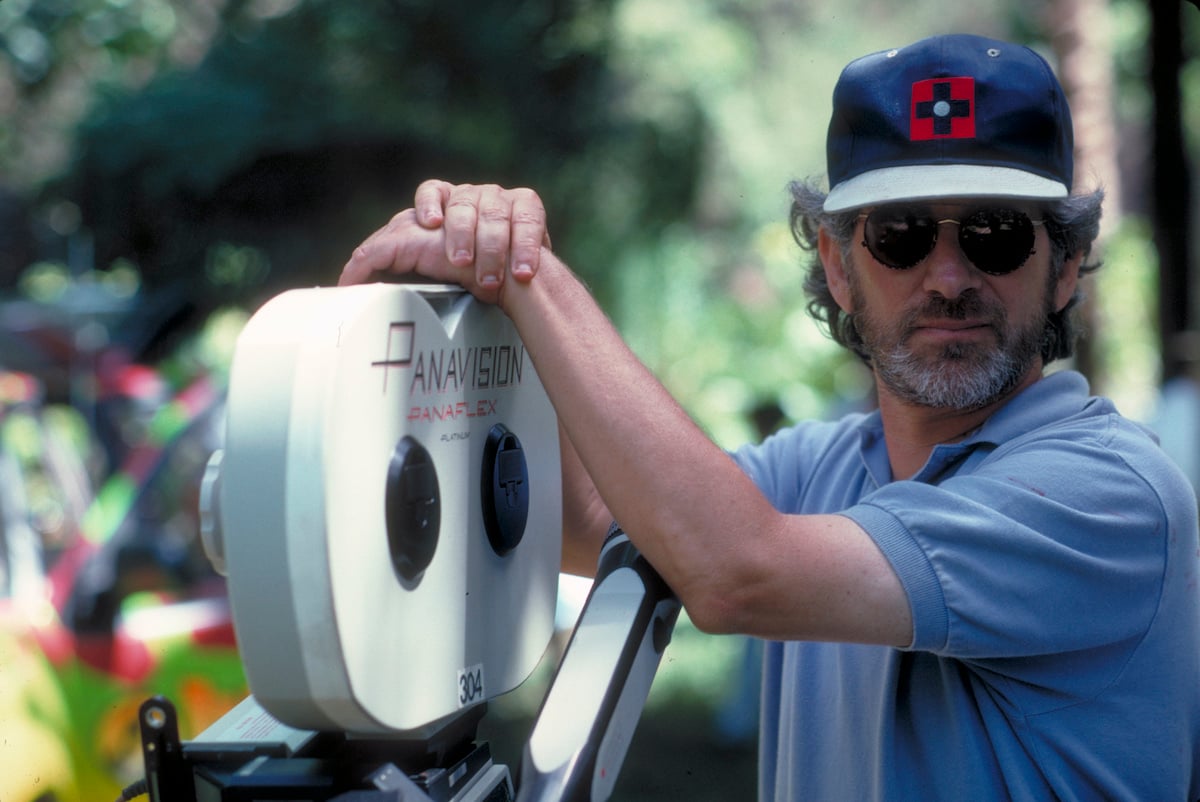 Steven Spielberg wears a hat and poses with a camera