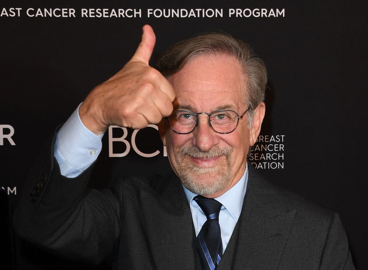 Steven Spielberg wears a suit and smiles while giving a thumbs up