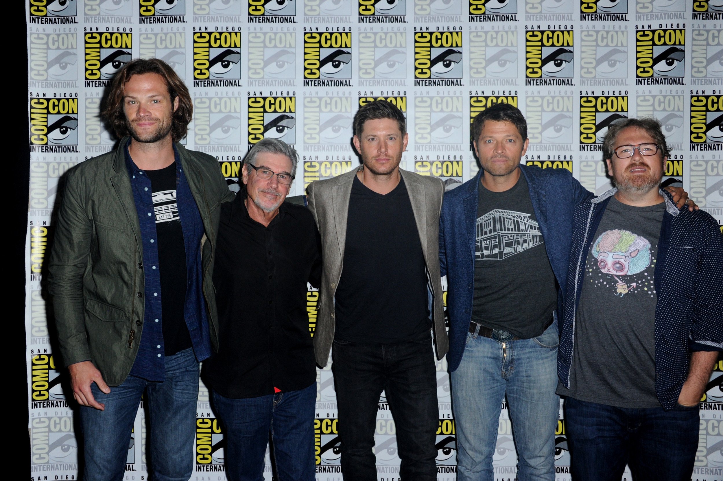 'Supernatural' stars Jared Padalecki, Jensen Ackles, and Misha Collins stand with their arms around writers and producers Robert Singer and Andrew Dabb at Comic-Con