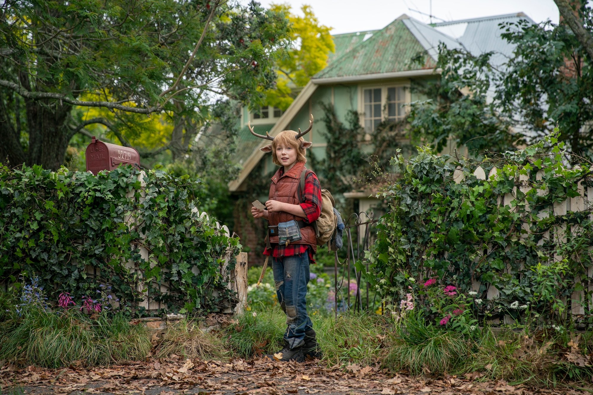 Gus from 'Sweet Tooth' standing in front of an overgrown lawn