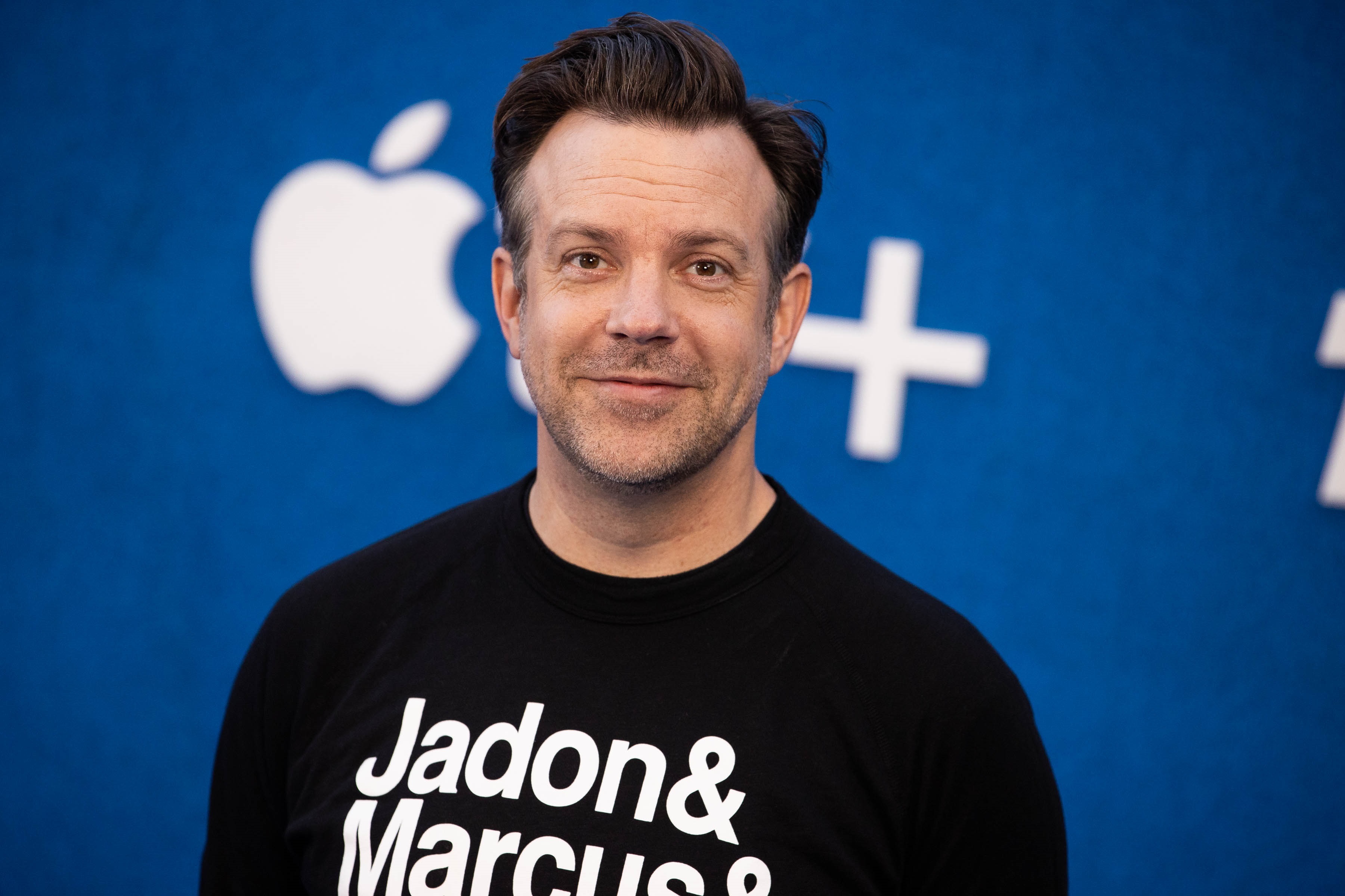 Jason Sudeikis smiling for photographers at the Ted Lasso Season 2 premiere awaiting the drop of new episodes to AppleTV+