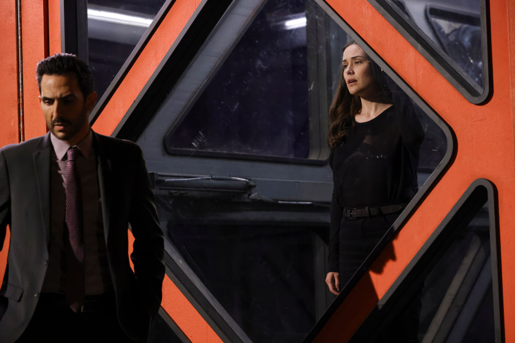 Amir Arison as Aram Mojtabai stands outside the container box that holds Megan Boone as Liz Keen.