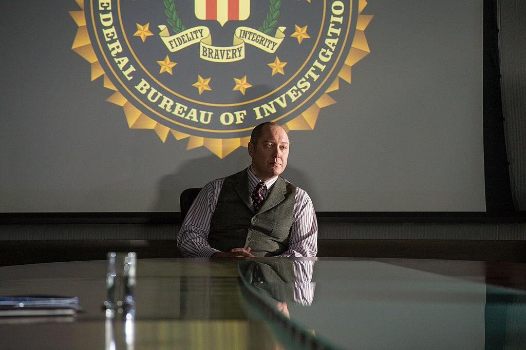 James Spader as Raymond 'Red' Reddington sits in a chair in the FBI headquarters.