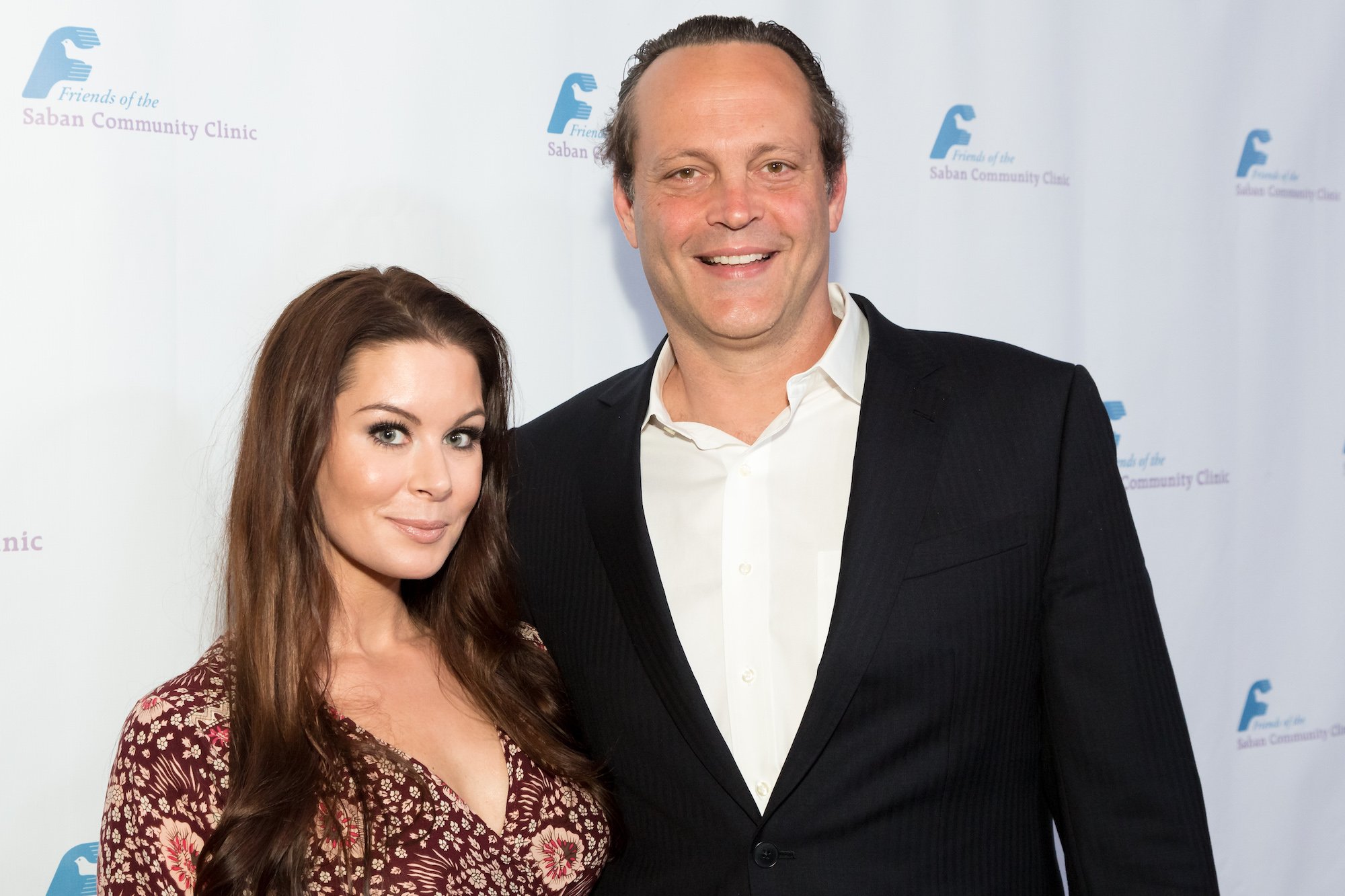 Kyla Weber and Vince Vaughn smiling in front of a white background