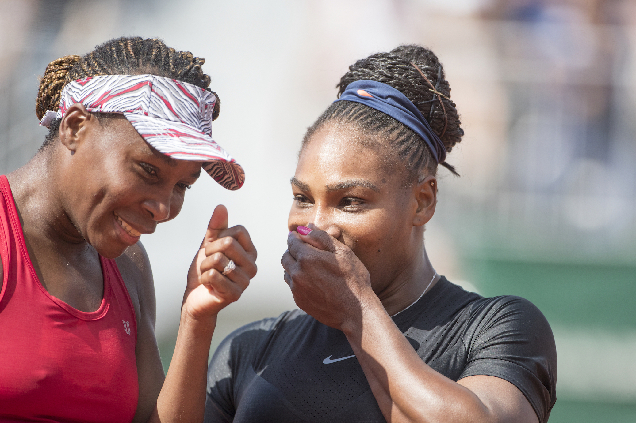 Serena Williams and Venus Williams laughing together on the tennis court