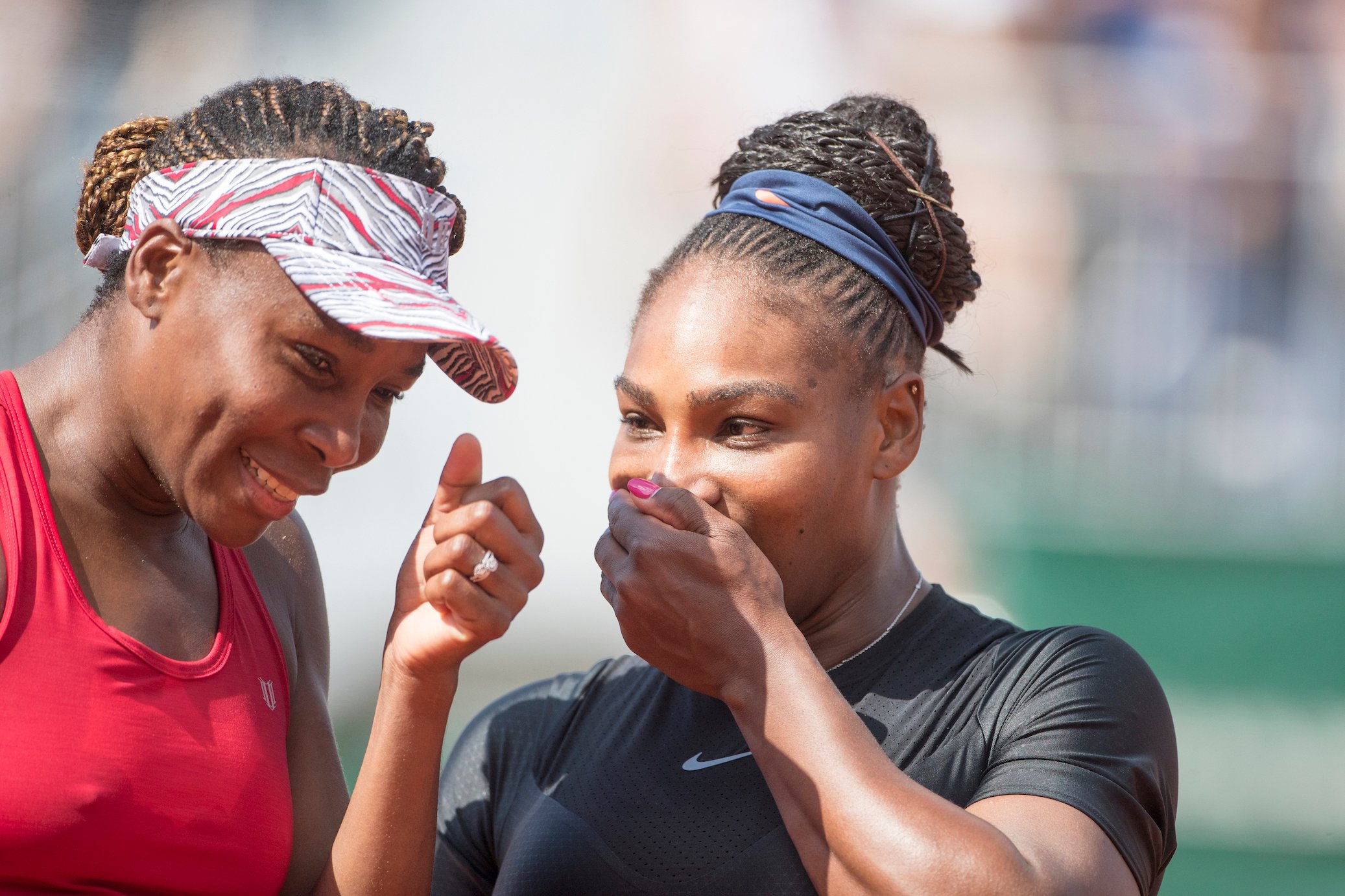 Serena Williams and Venus Williams laughing together on the tennis court