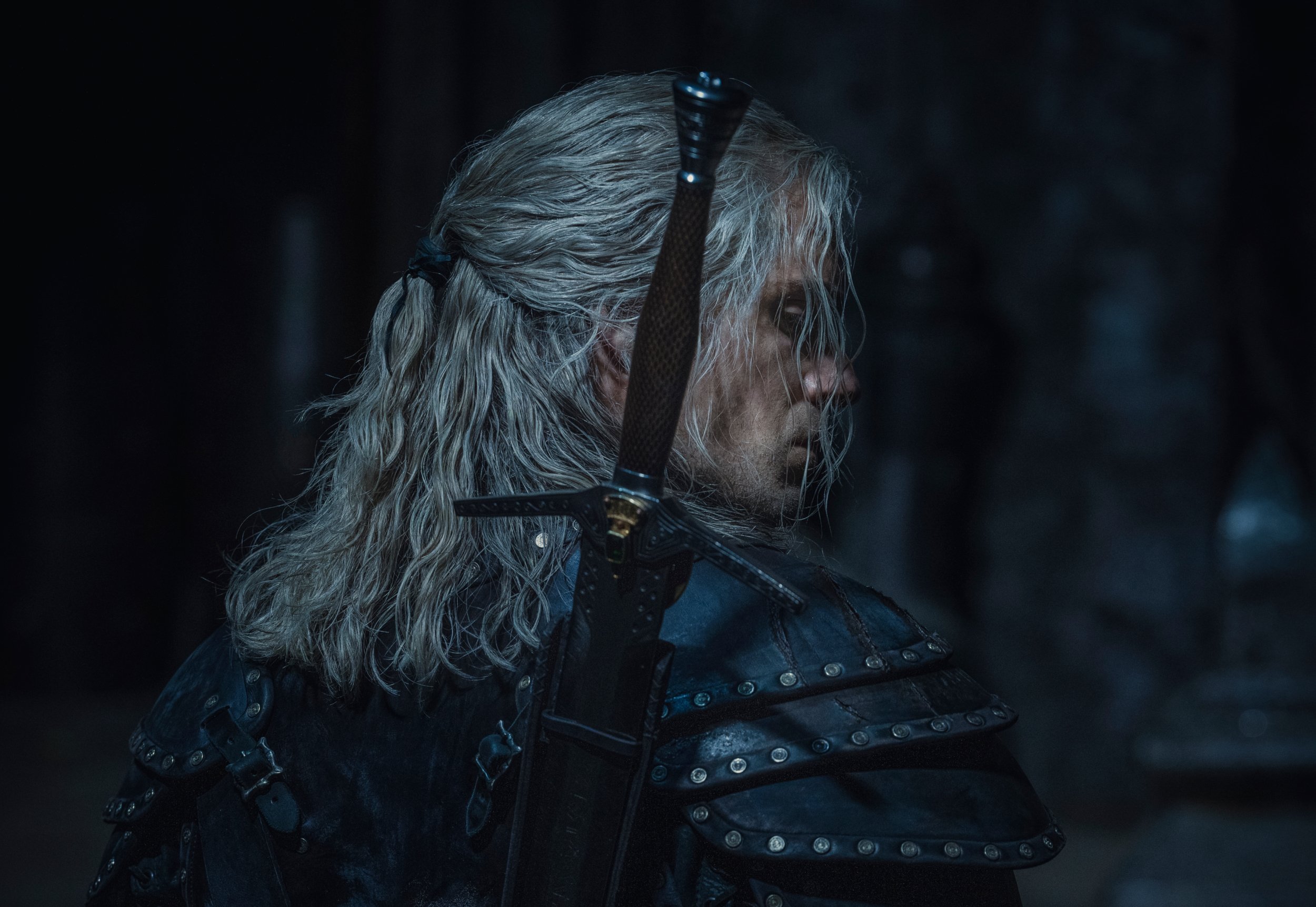 Henry Cavill as Witcher Geralt of Rivia wearing armor and carrying a sword