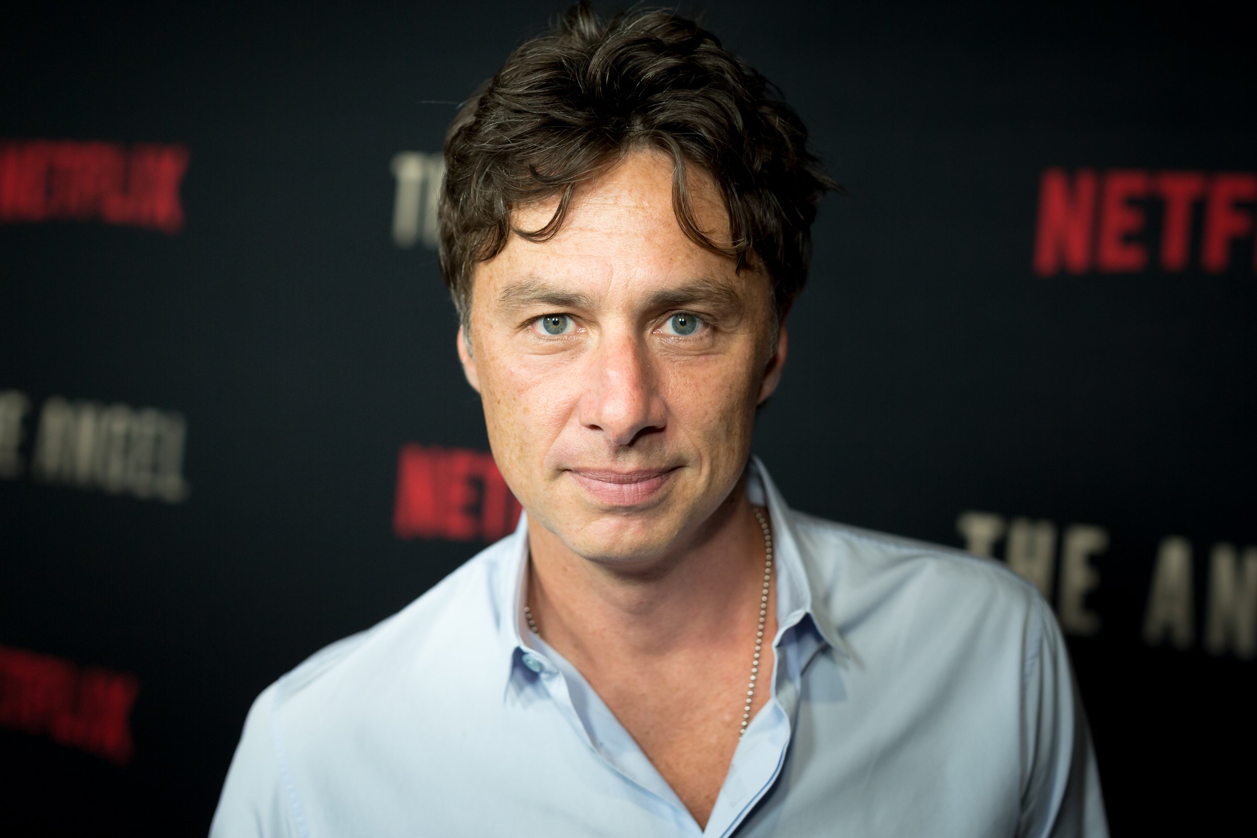 'Scrubs' star Zach Braff wears a blue collared shirt and stands in front of a Netflix wall