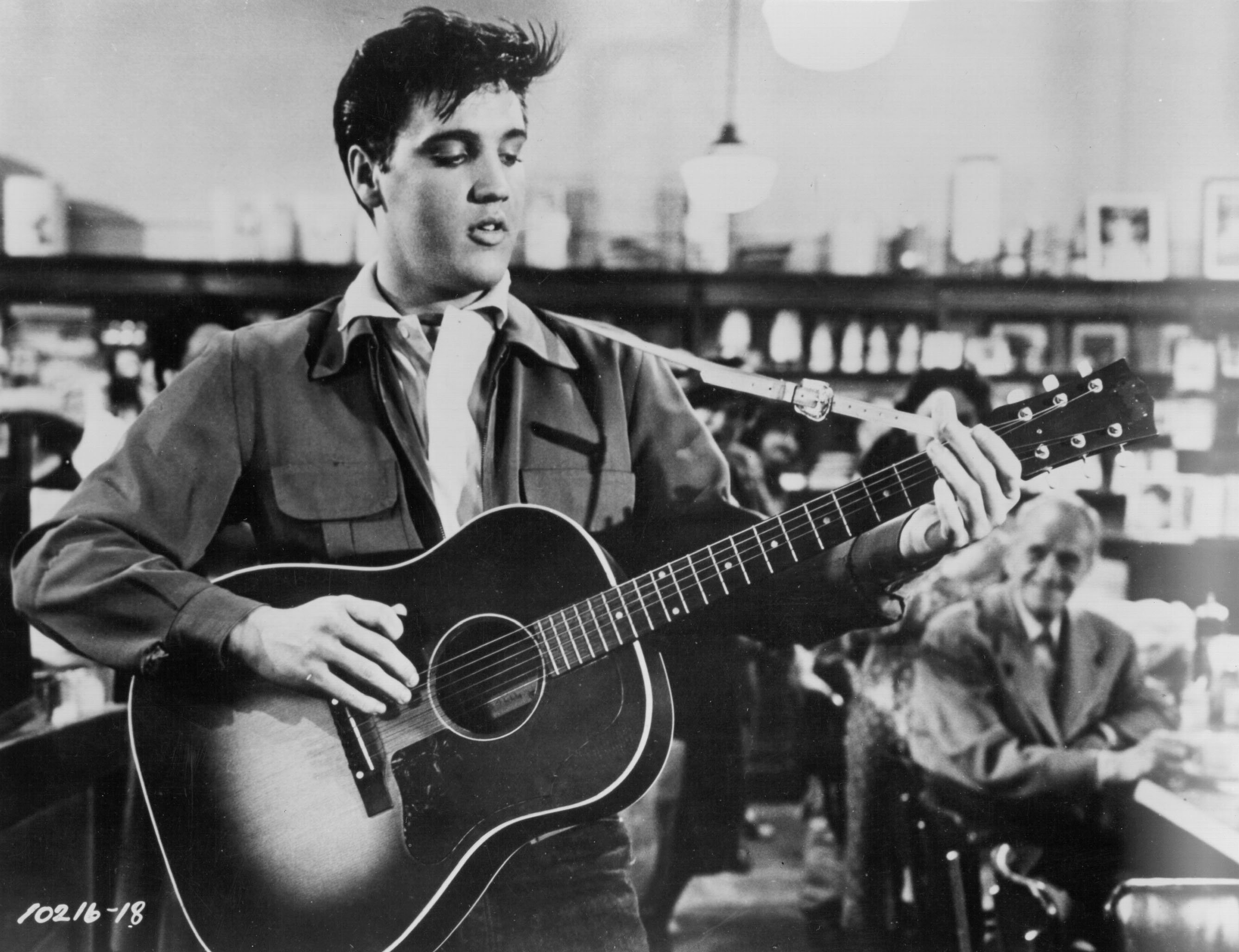 Elvis Presley playing one of his songs on a guitar