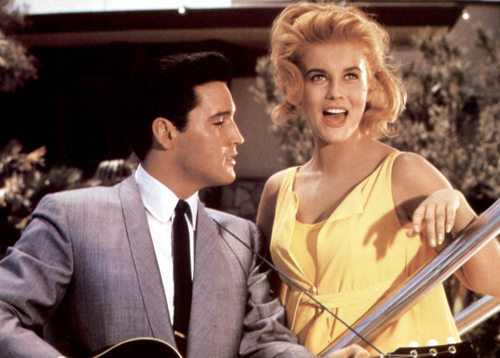 Elvis Presley holding a guitar and standing next to Ann-Margret