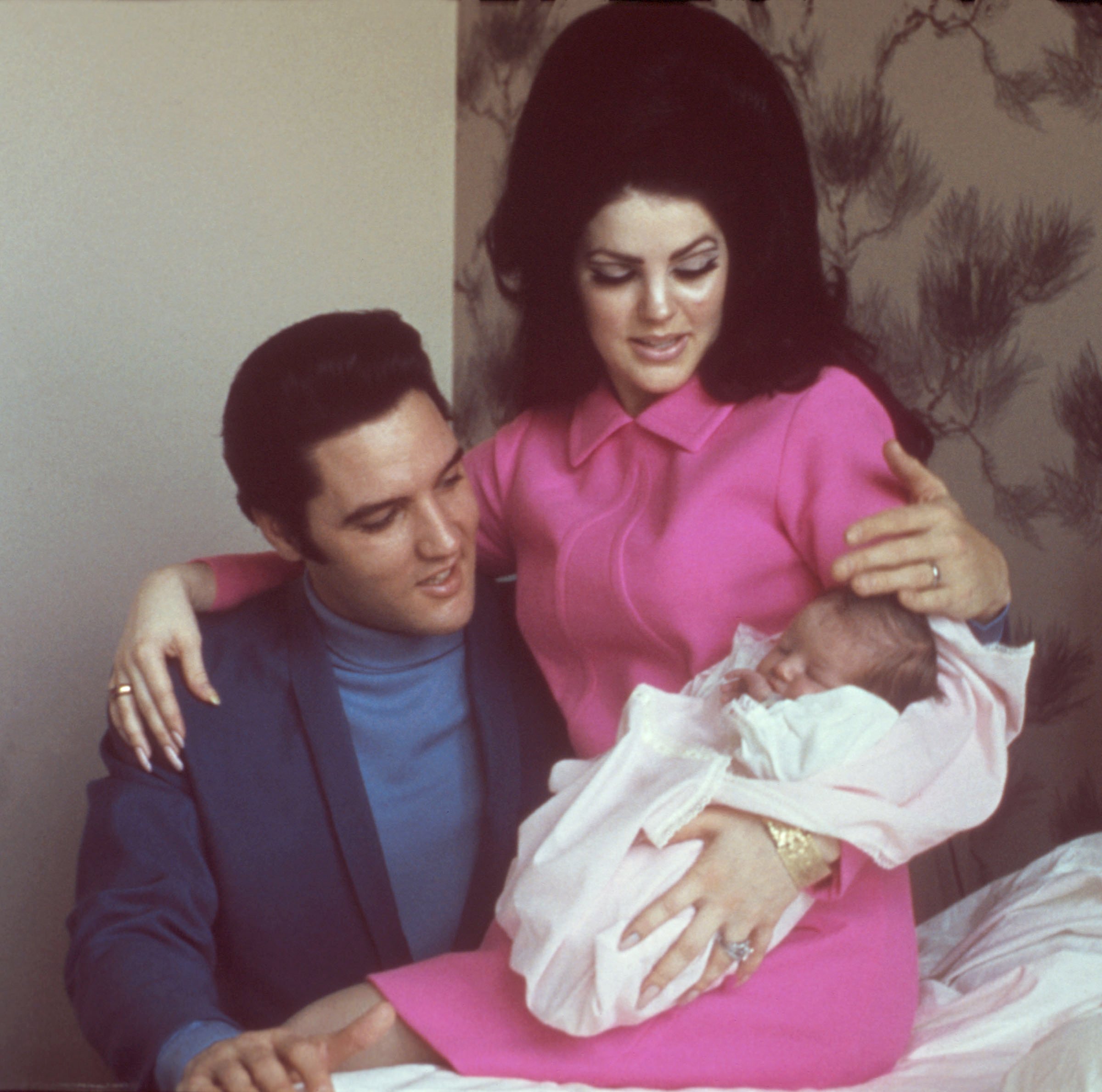 Priscilla Presley holding baby Lisa Marie Presley and putting her arm around Elvis Presley