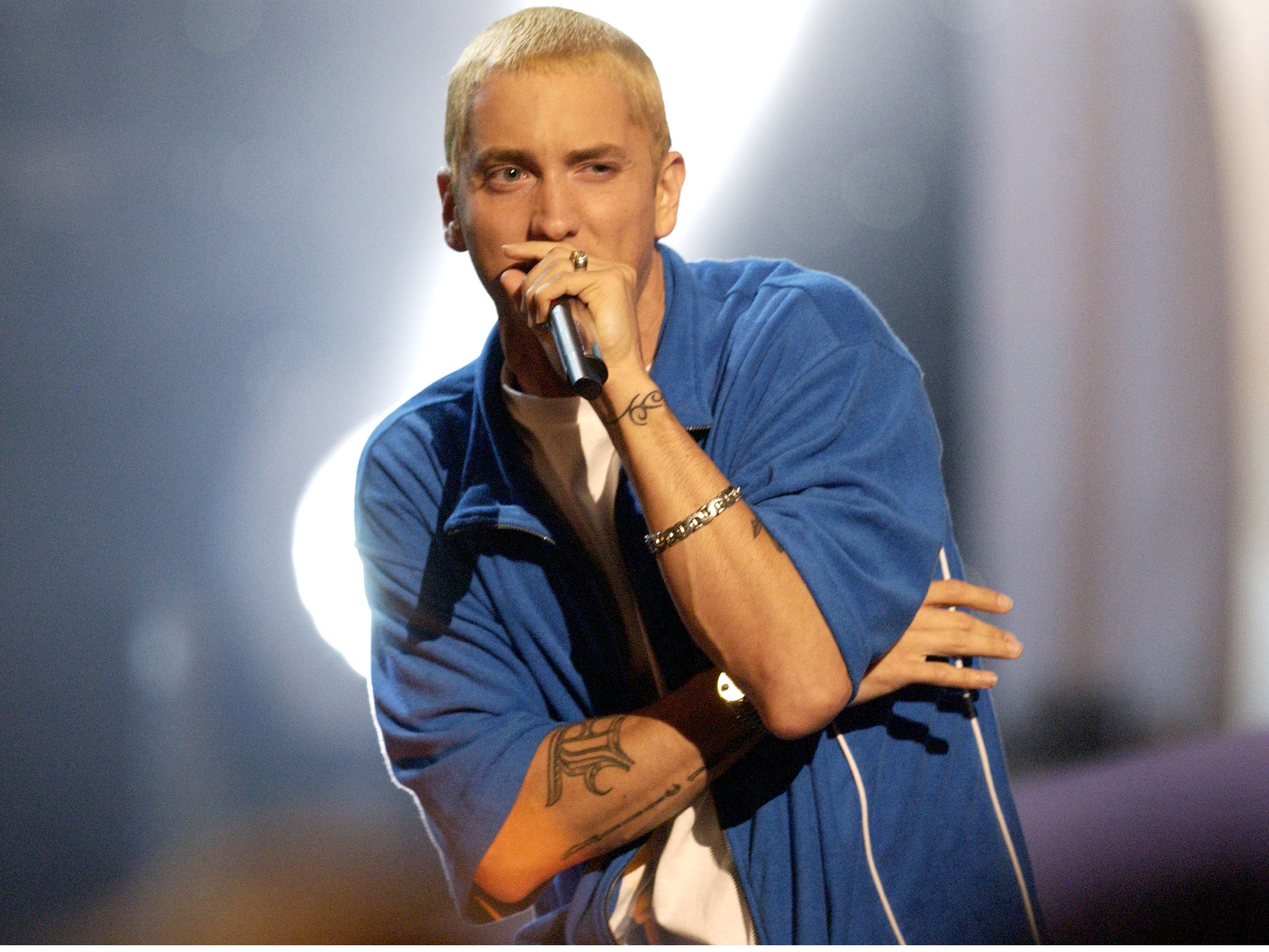 Eminem wearing a blue jacket and holding a microphone